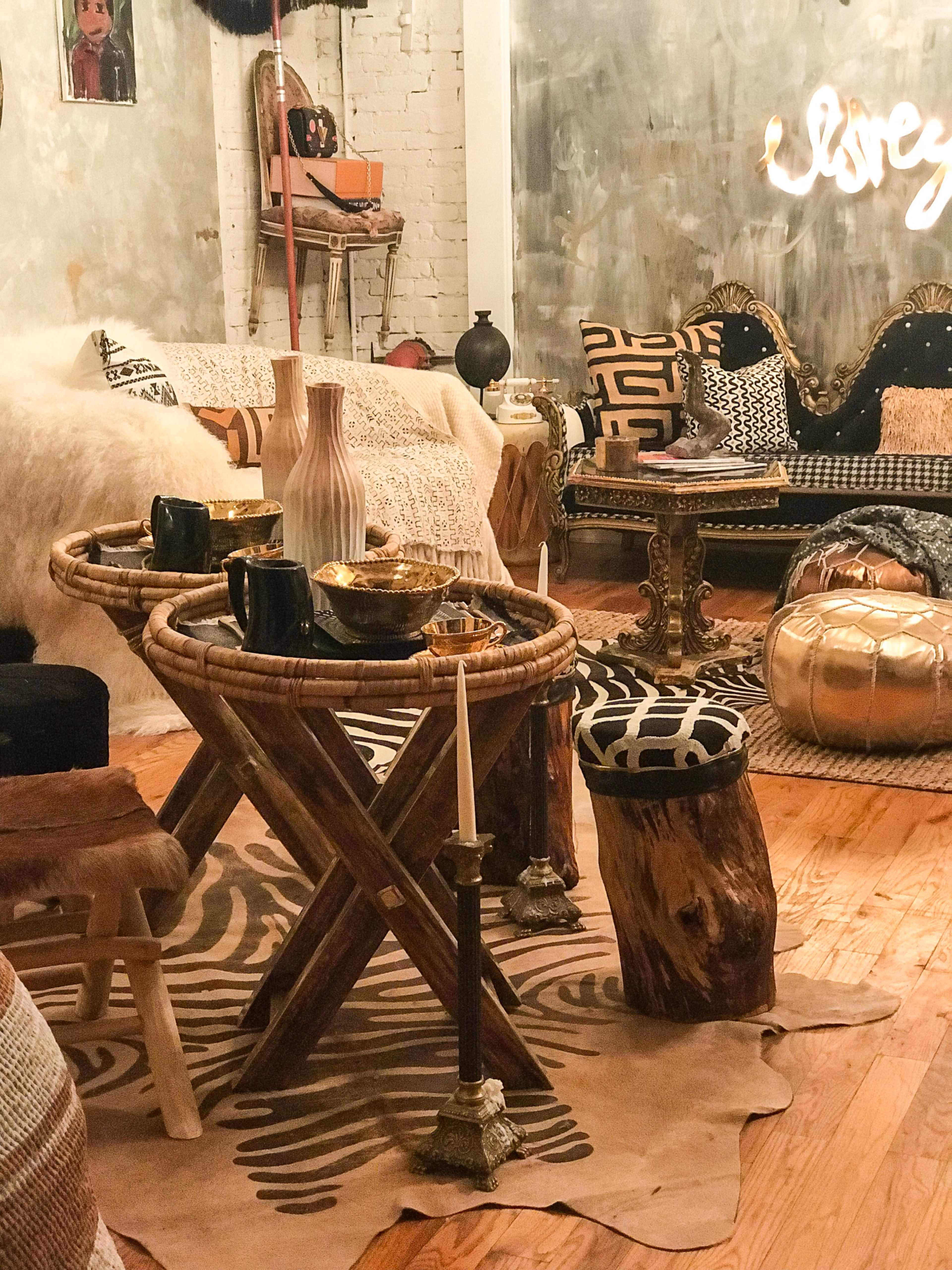 A cozy living room space with eclectic furniture, featuring a wooden coffee table, decorative bowls, and a mix of patterned cushions and rugs.