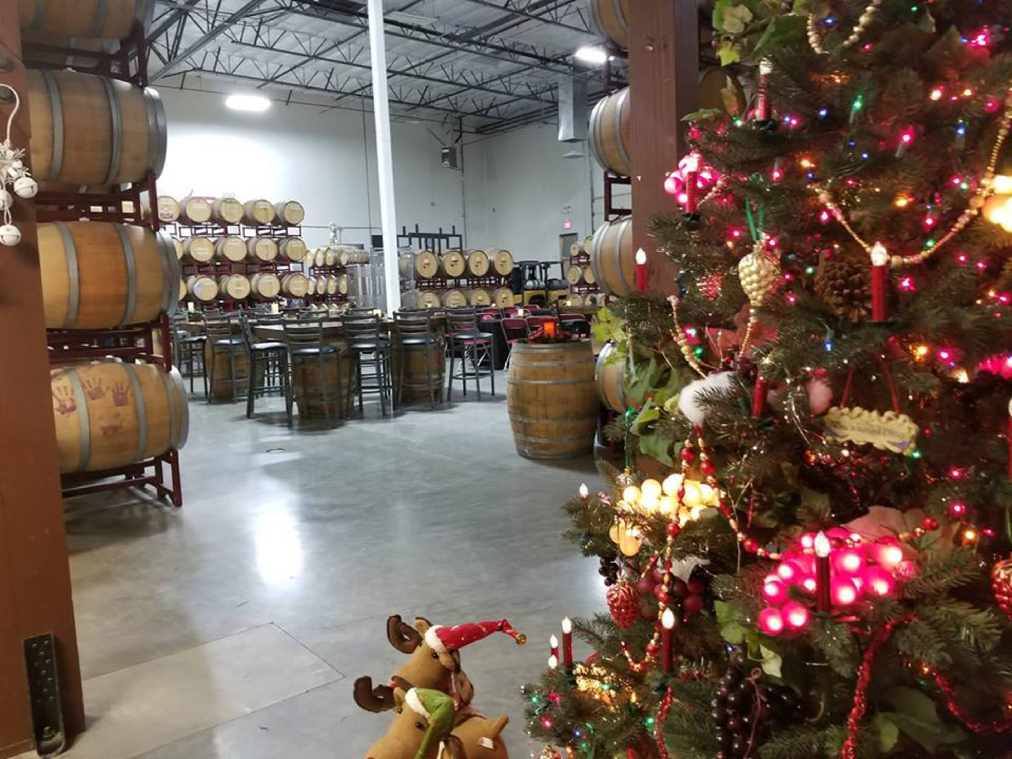 A winery interior with wooden barrels in the background and a decorated Christmas tree in the foreground.