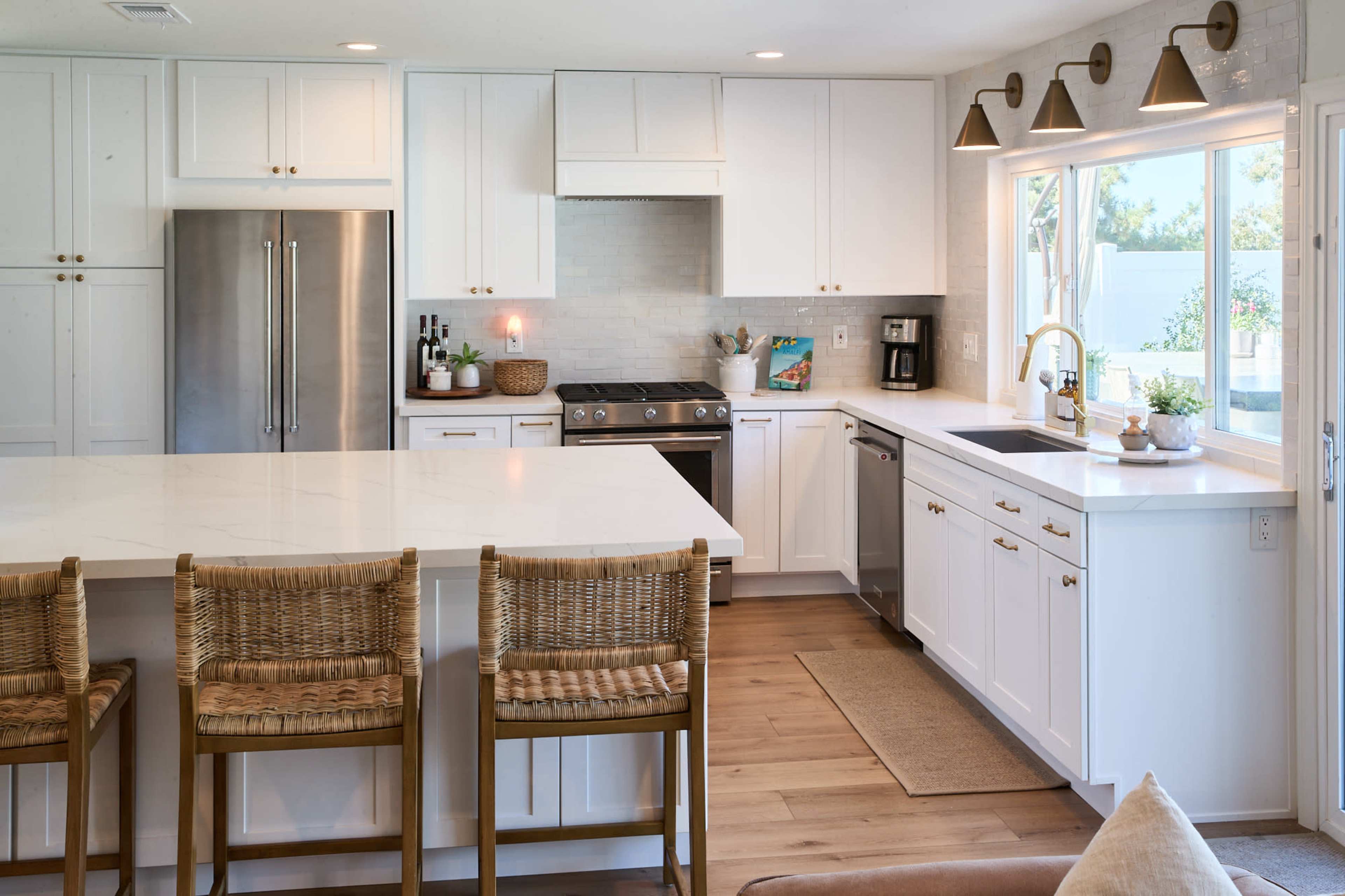 A modern kitchen with white cabinetry, stainless steel appliances, and a large island with bar stools.
