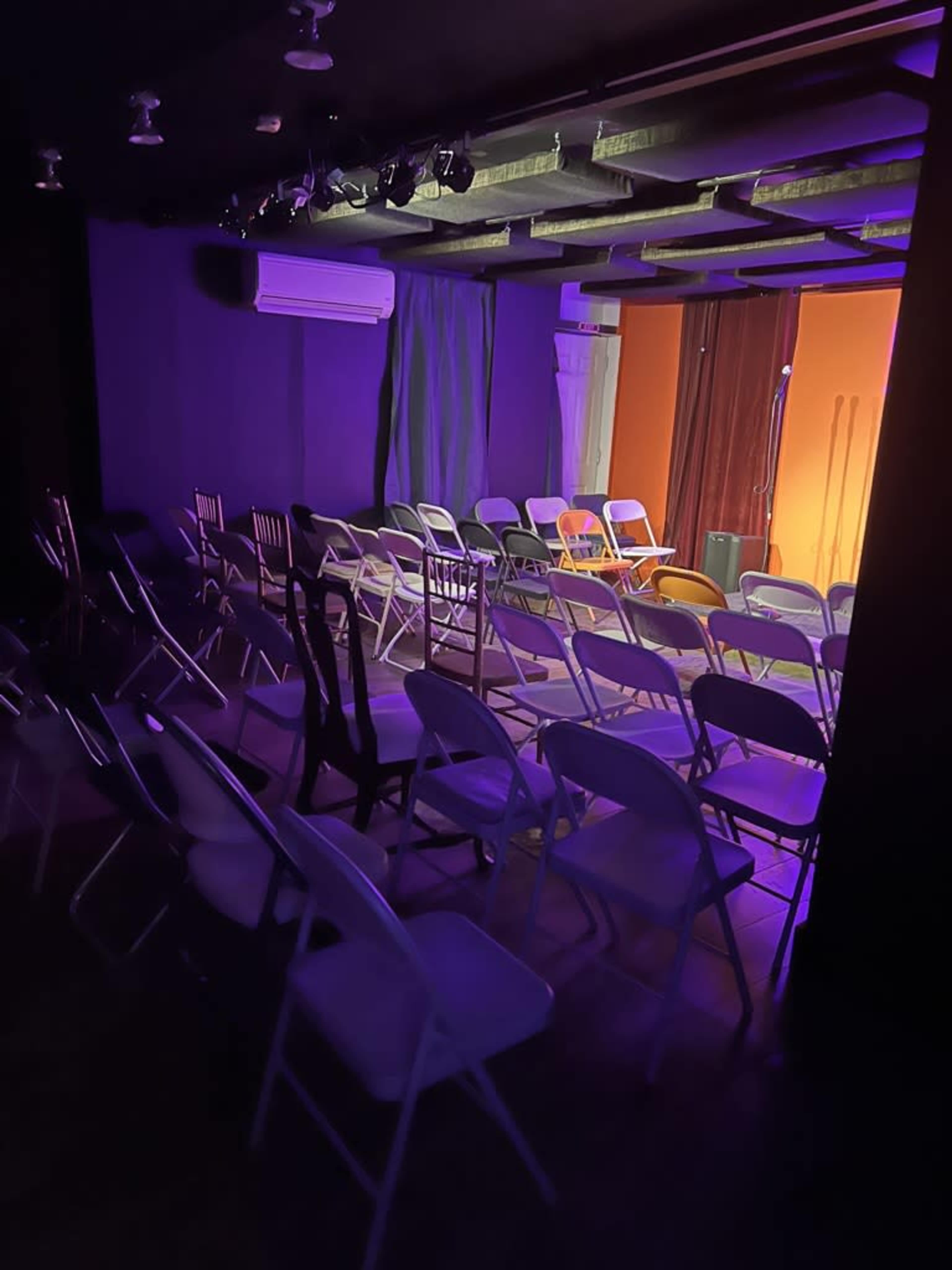 A dimly lit small theater with rows of chairs arranged for an event.