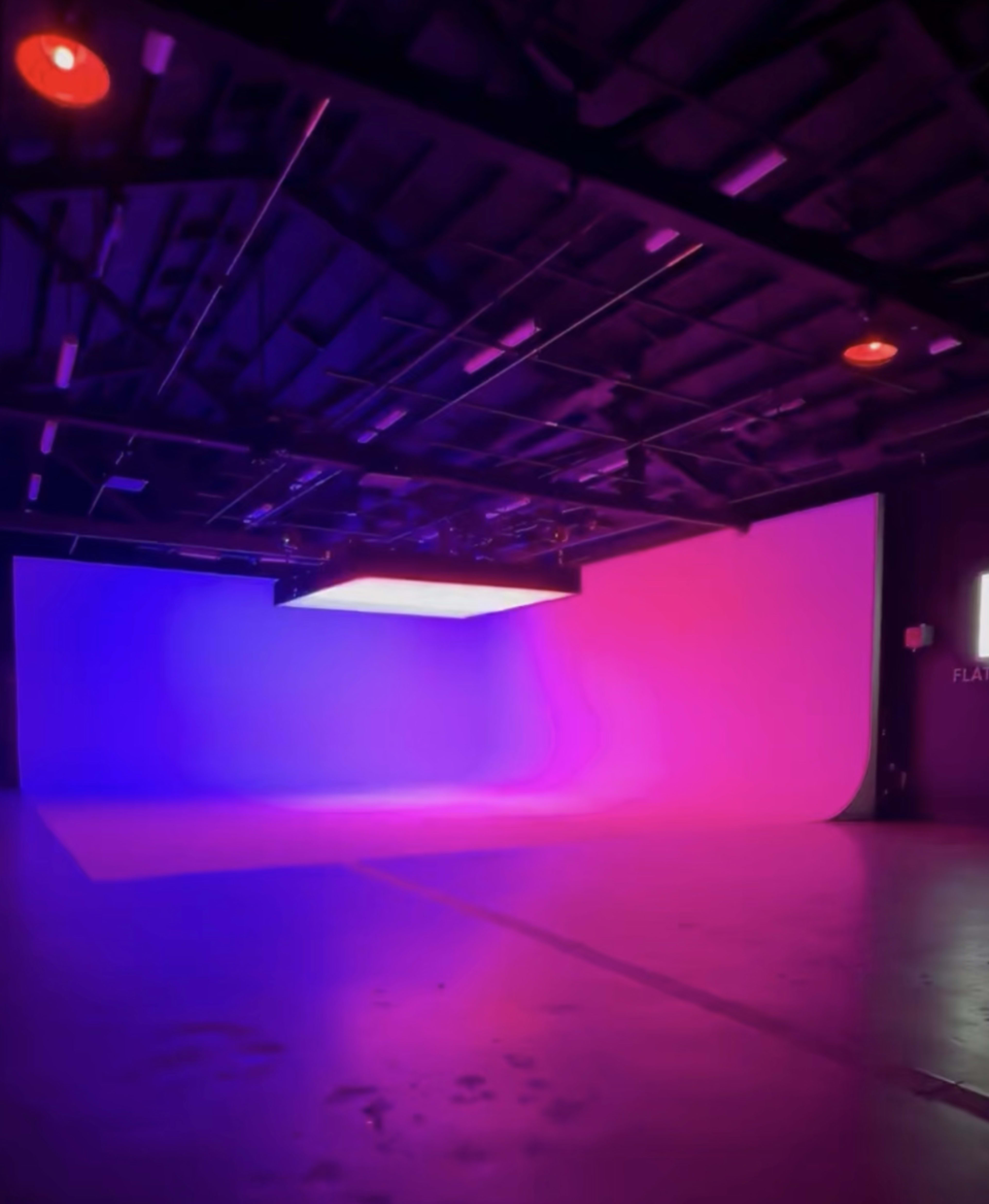 The image shows a photographic studio with a gradient backdrop of purple and blue lighting.