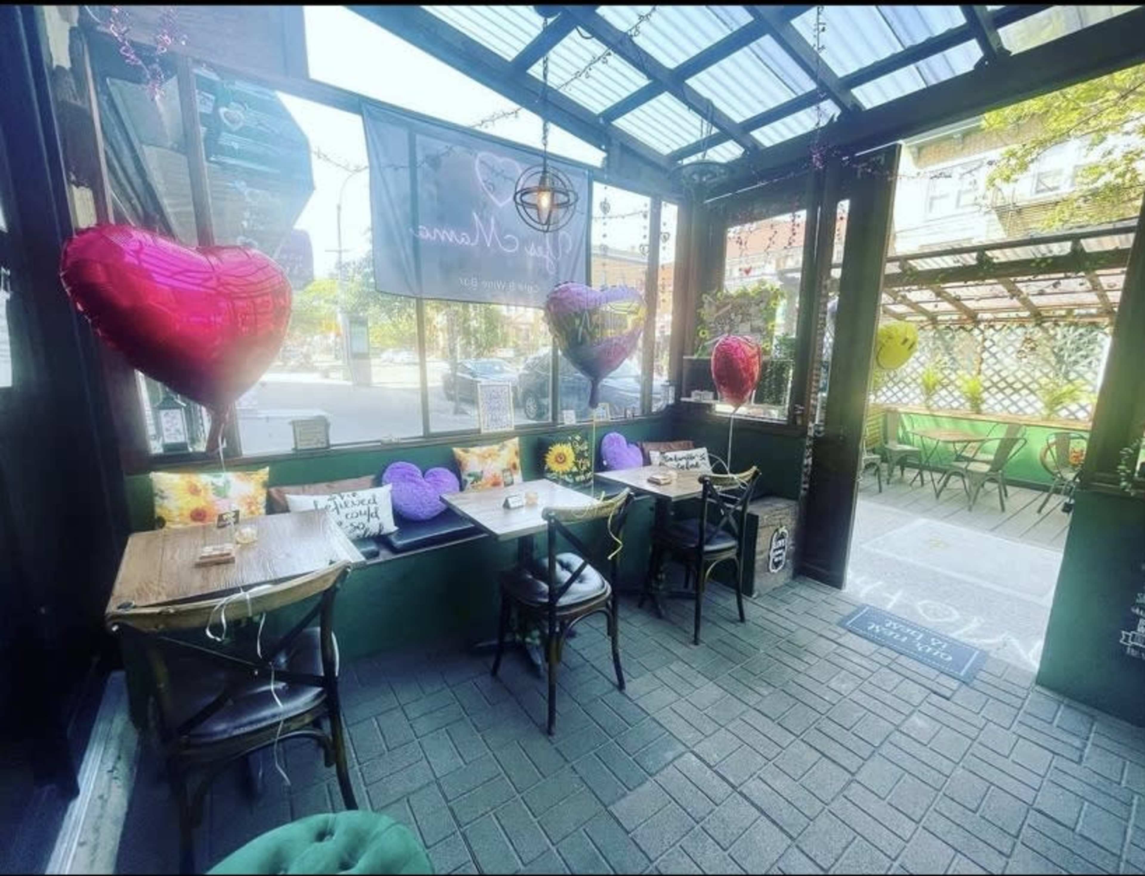 A cozy cafe patio adorned with heart-shaped balloons and tables set for guests.