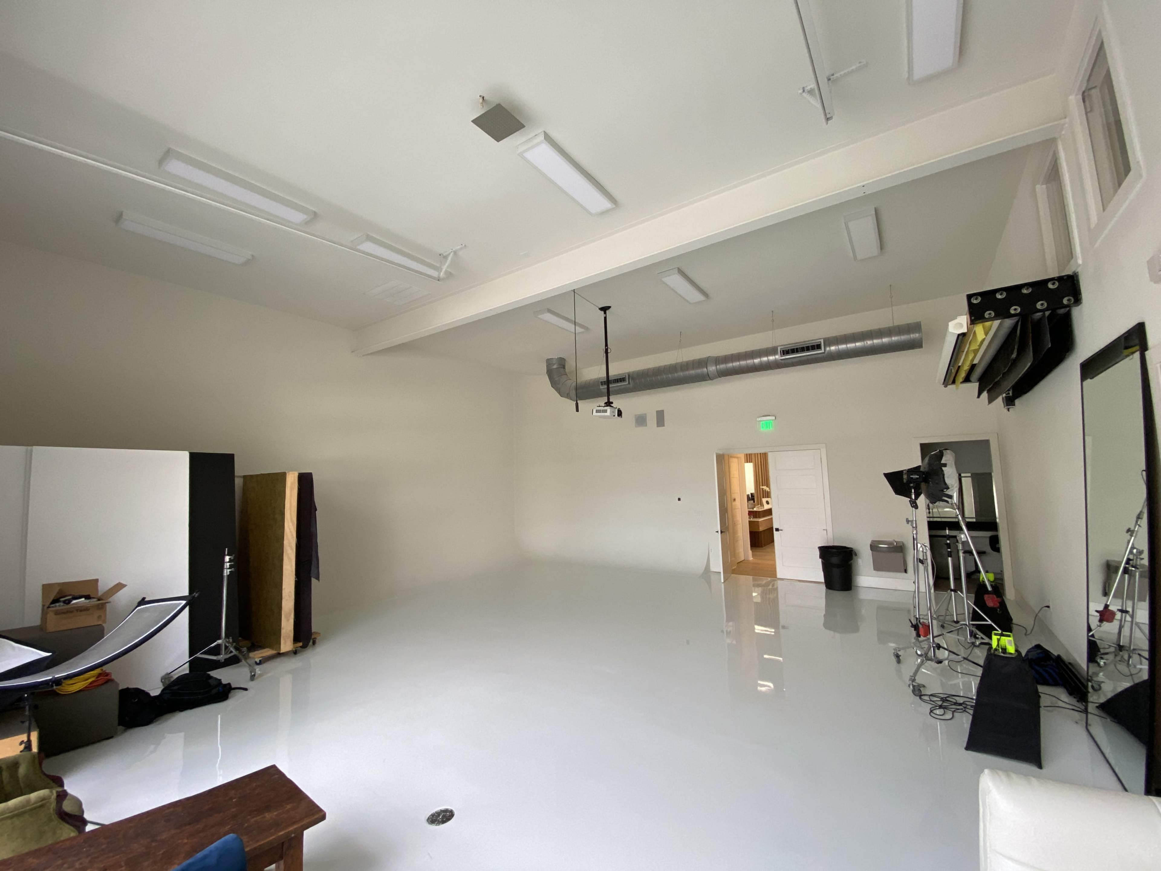 A large, empty studio space featuring a high ceiling, white walls, and a polished floor.