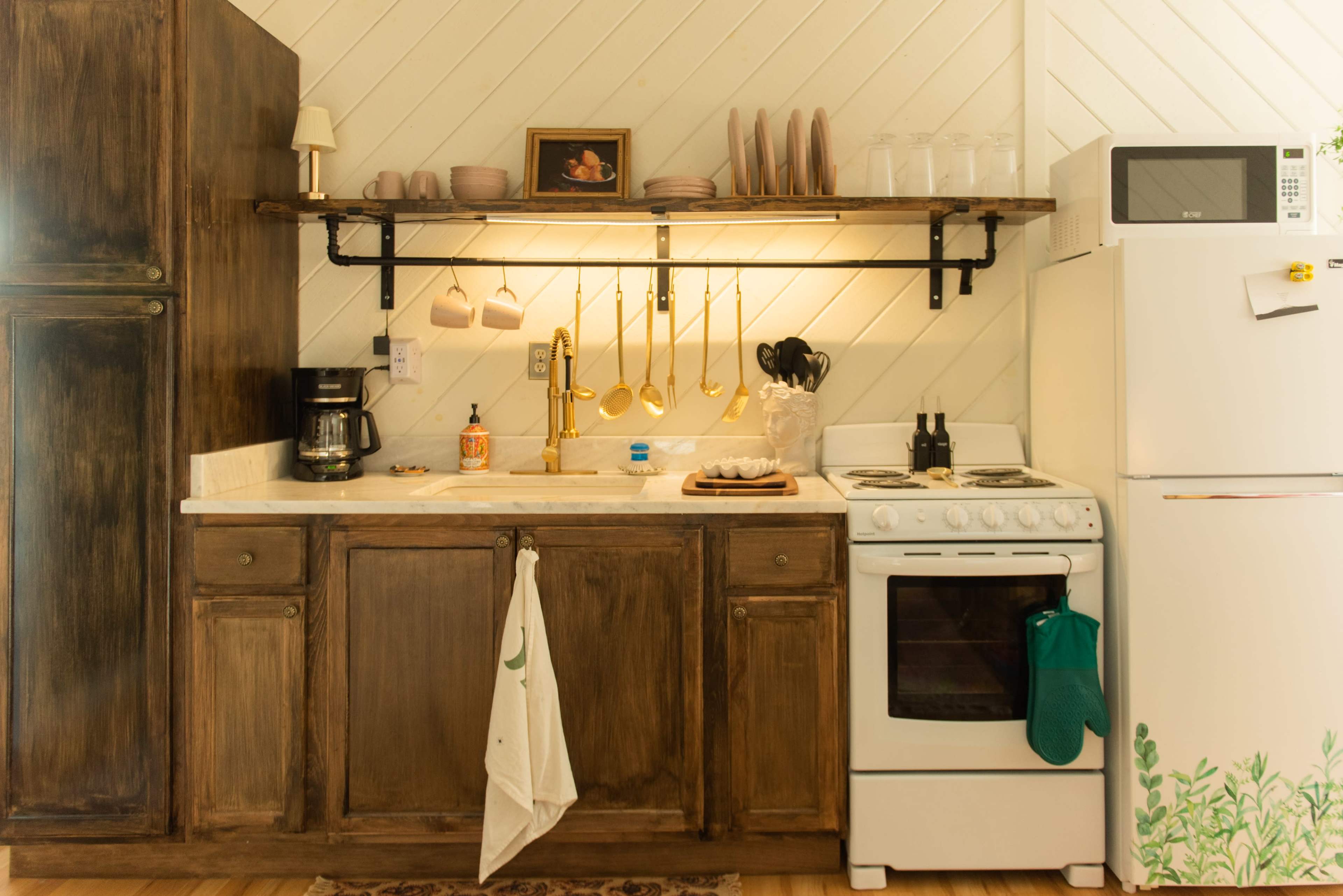 A kitchen with wooden cabinets, a white stove, a refrigerator, and open shelving displaying dishes and cooking utensils.