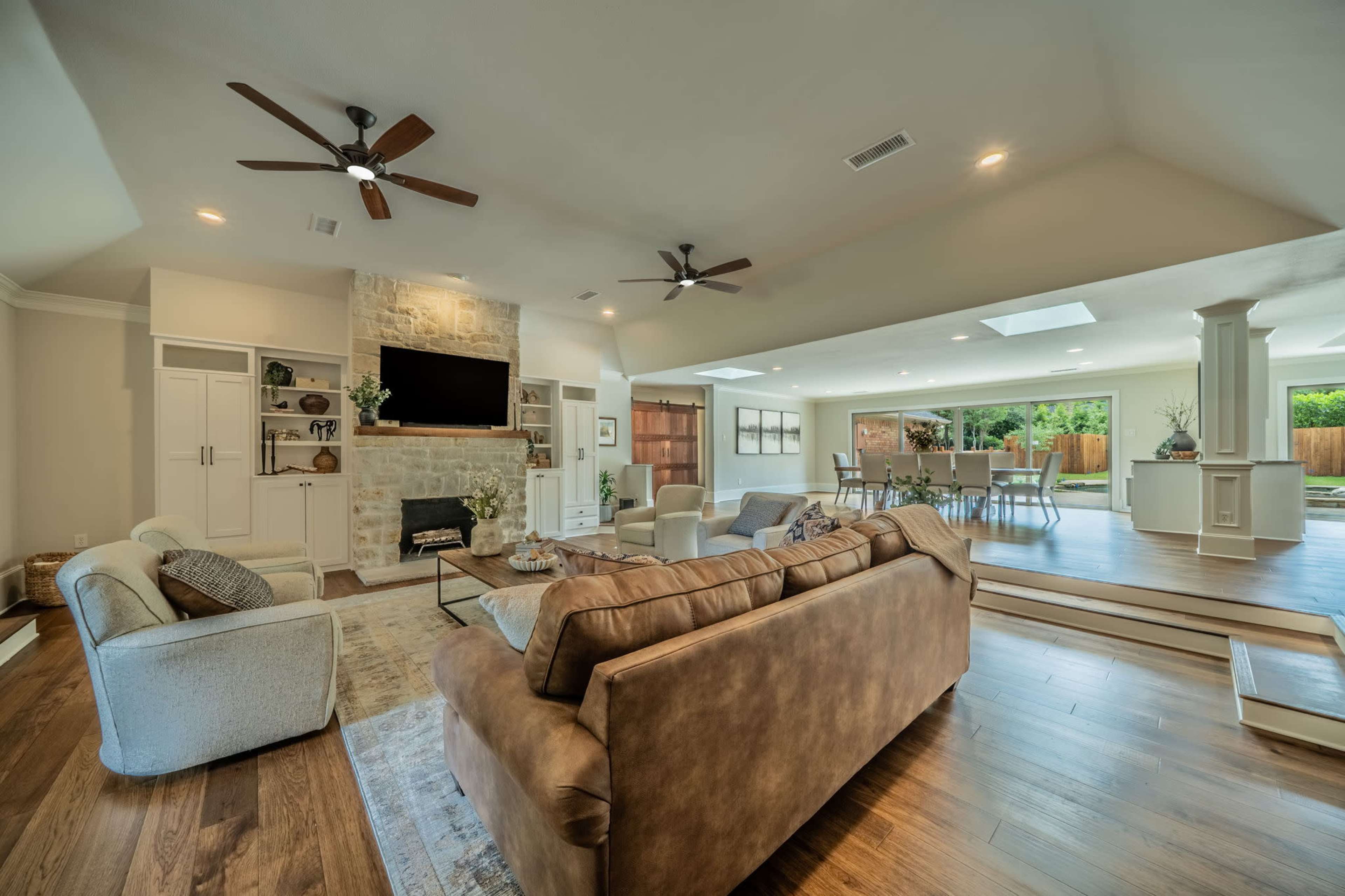 The image shows a spacious living room with a large sofa, a stone fireplace, and a dining area visible in the background.