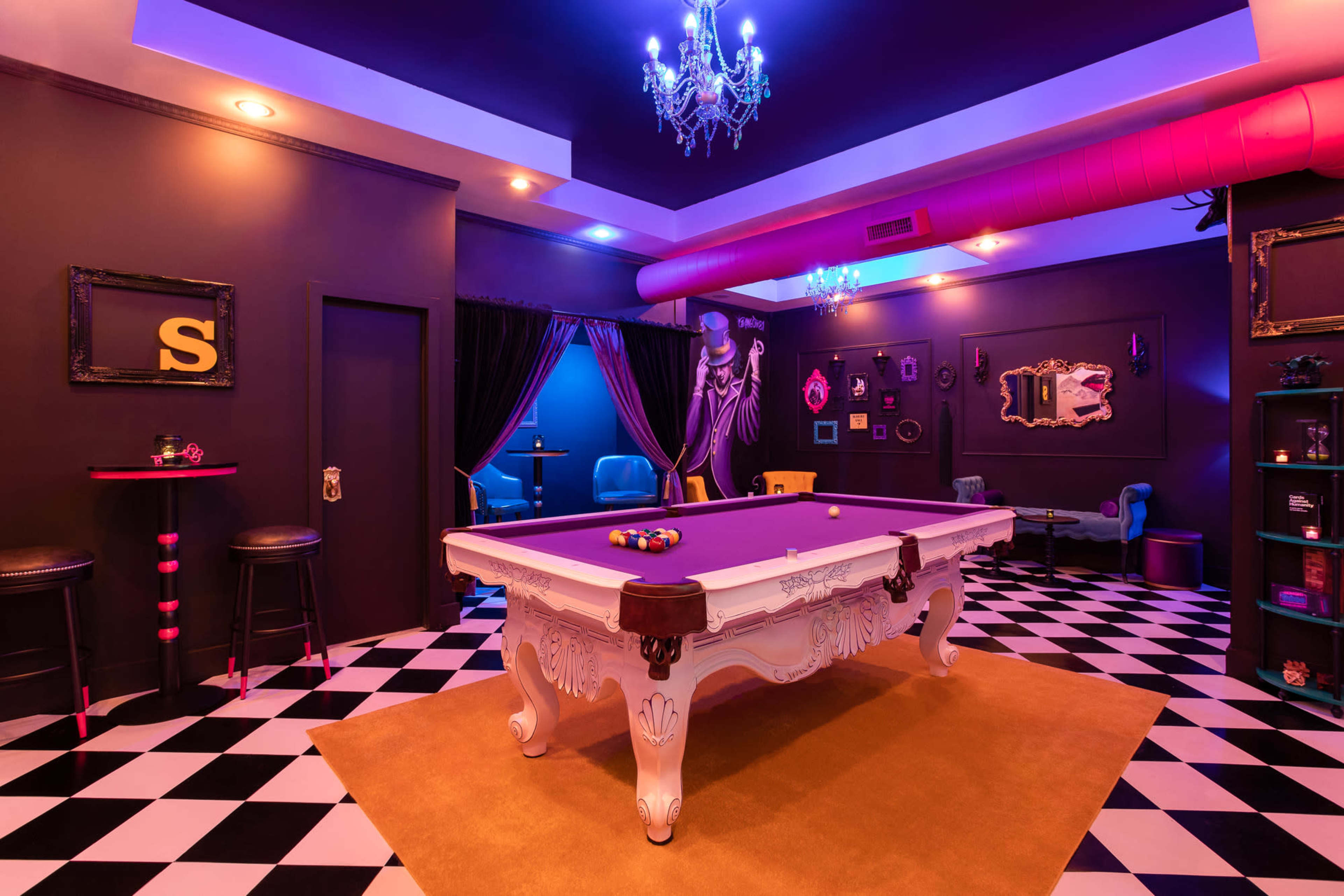 A stylish room features a purple billiards table at its center, surrounded by black and white checkered flooring and vibrant decorations.