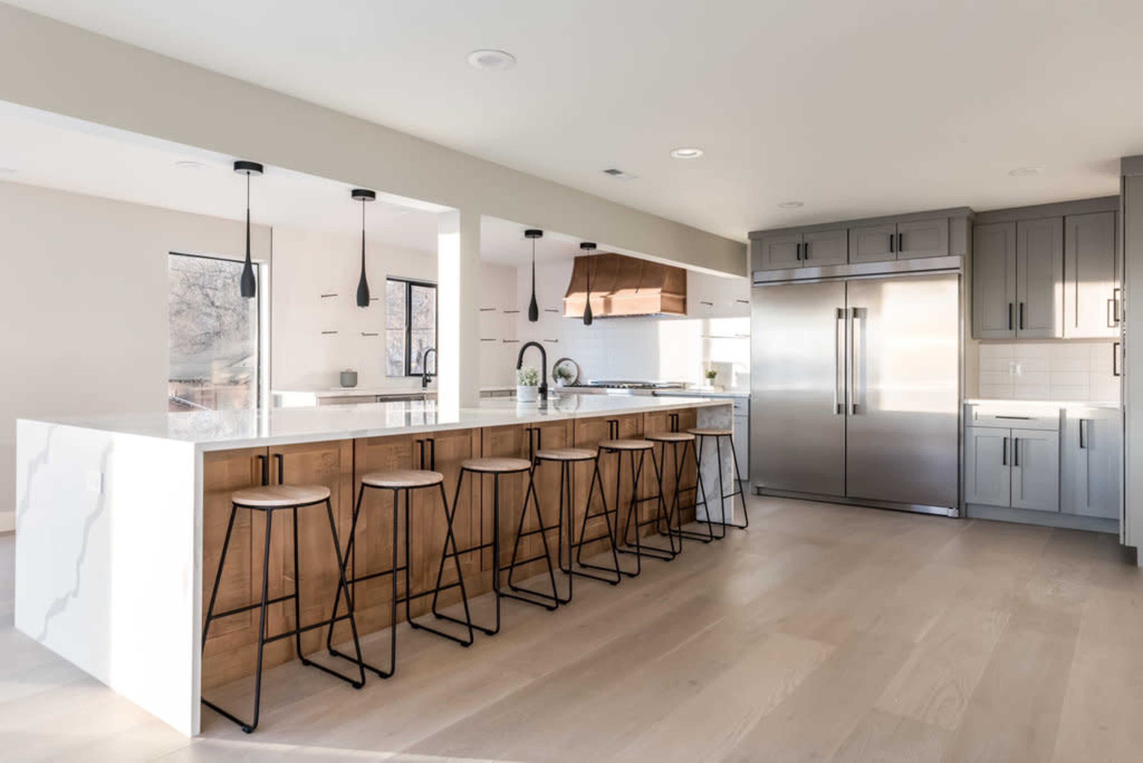 A modern kitchen featuring a large island with high stools, stainless steel appliances, and a light color palette.