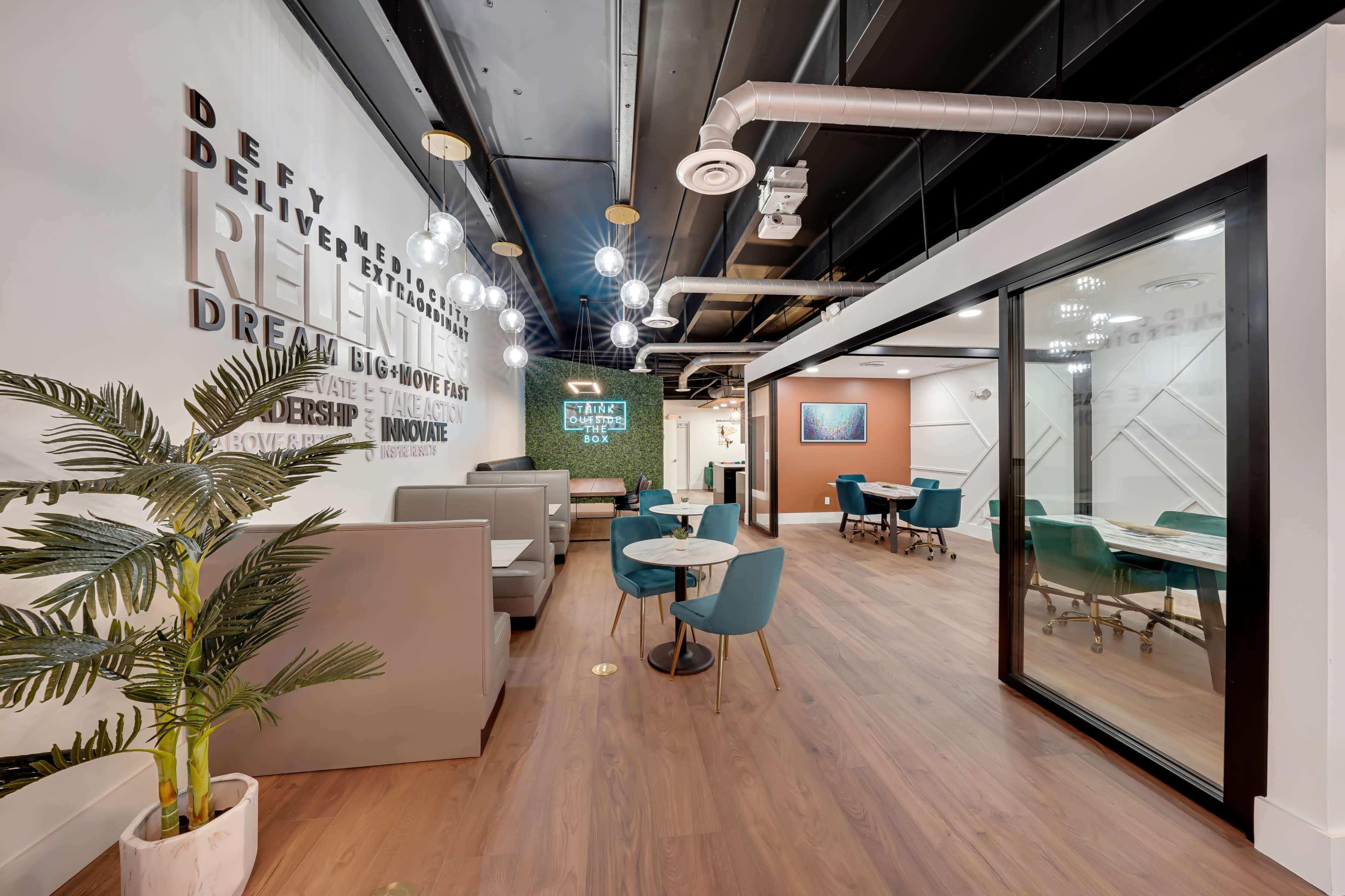 A modern office space with seating areas, dining tables, and walls featuring motivational text.