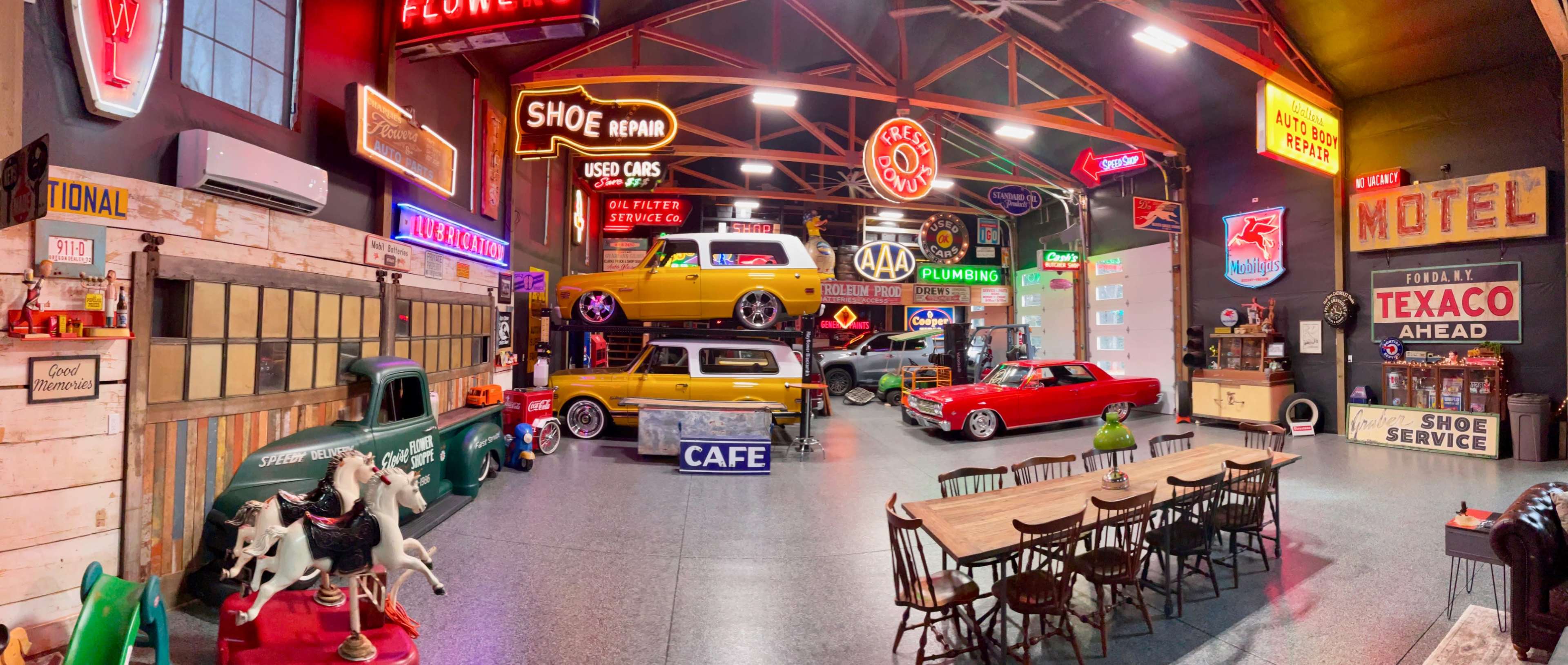 The image shows a vintage garage filled with colorful neon signs, classic cars, and retro decor.