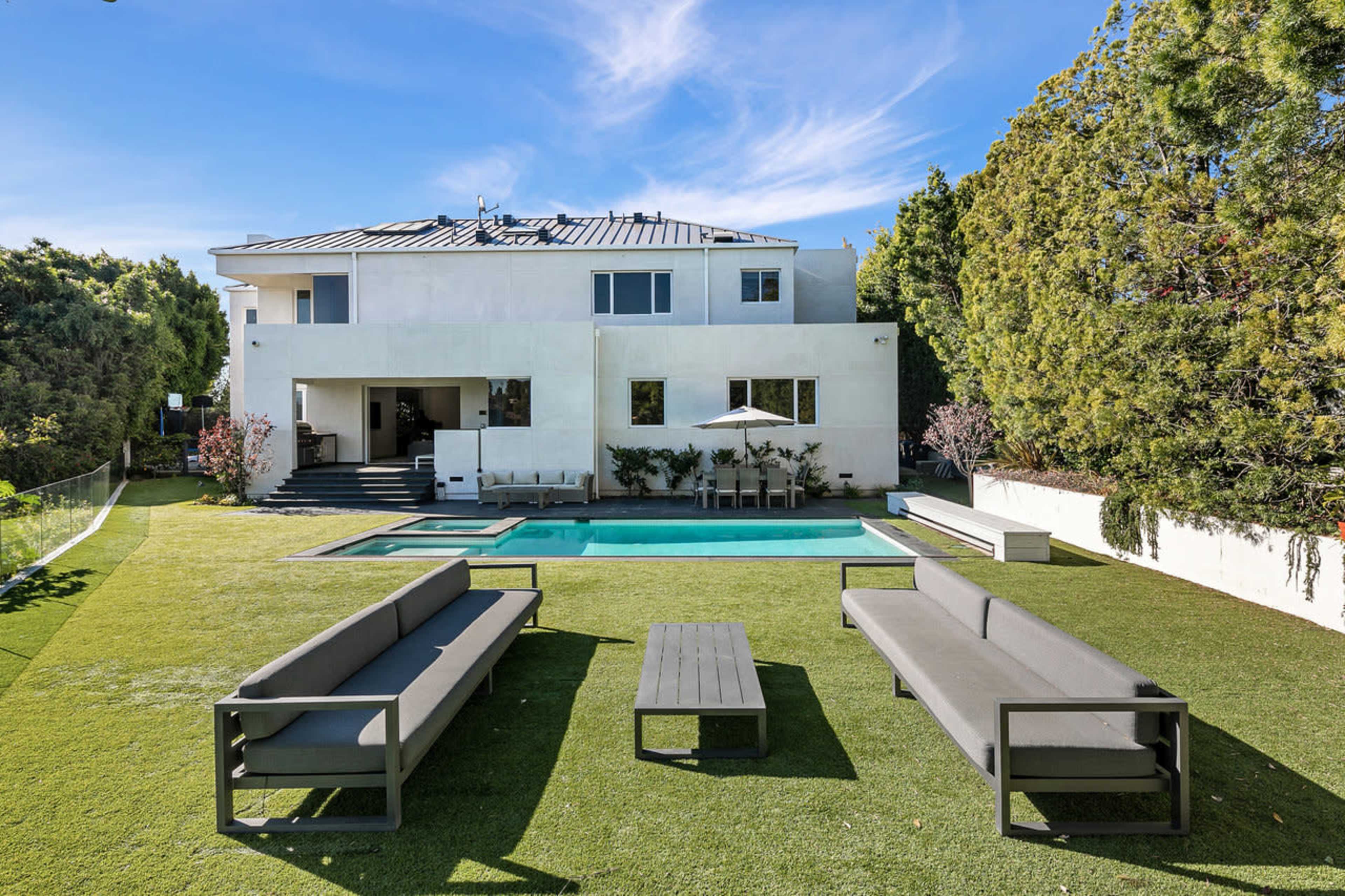 A modern house with a swimming pool and seating area set in a landscaped yard.