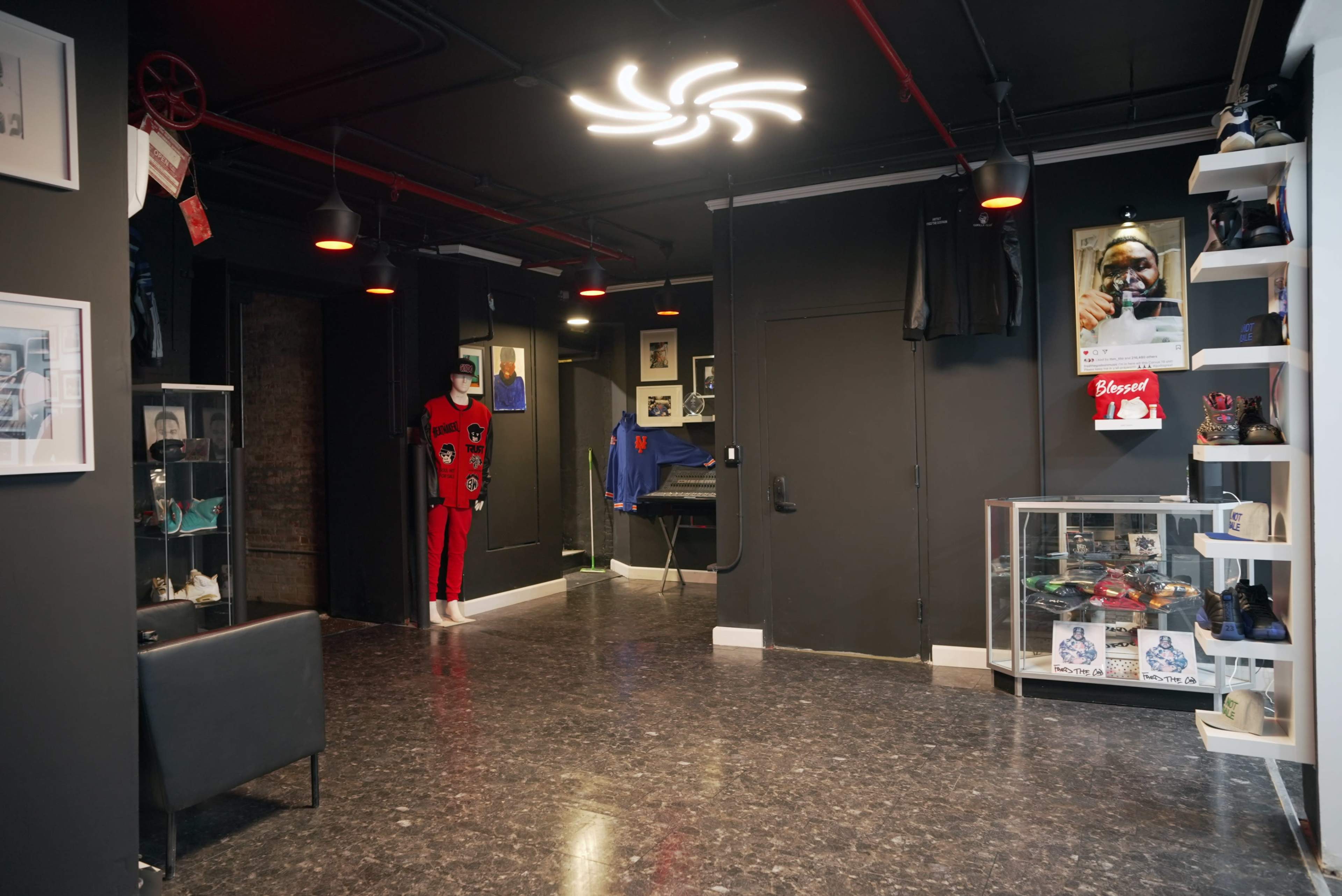 The interior of a modern gallery features a polished floor, dim lighting, and displays of clothing and art on the walls.