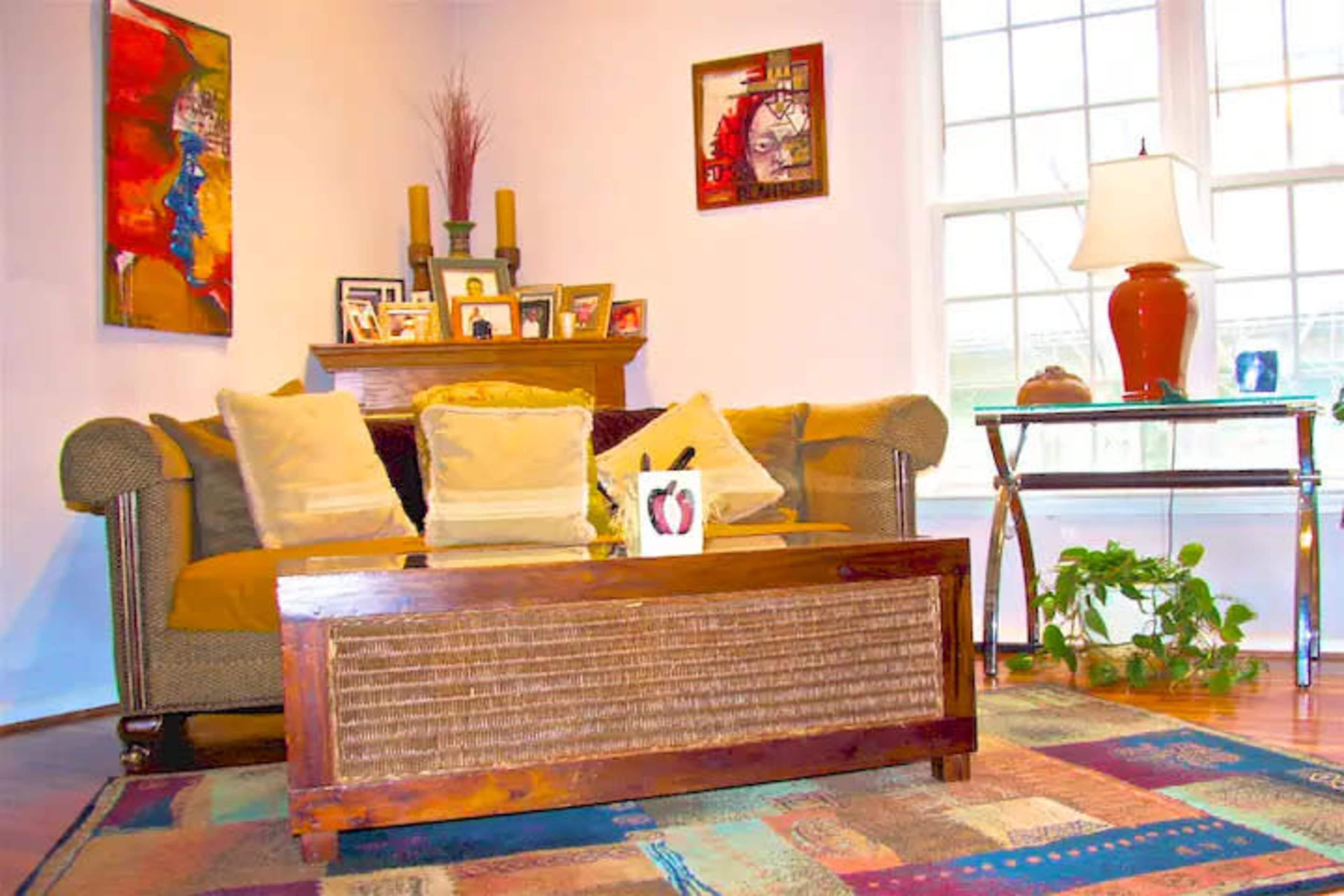 A living room with a brown couch, a wooden coffee table, and a decorative lamp beside a window.