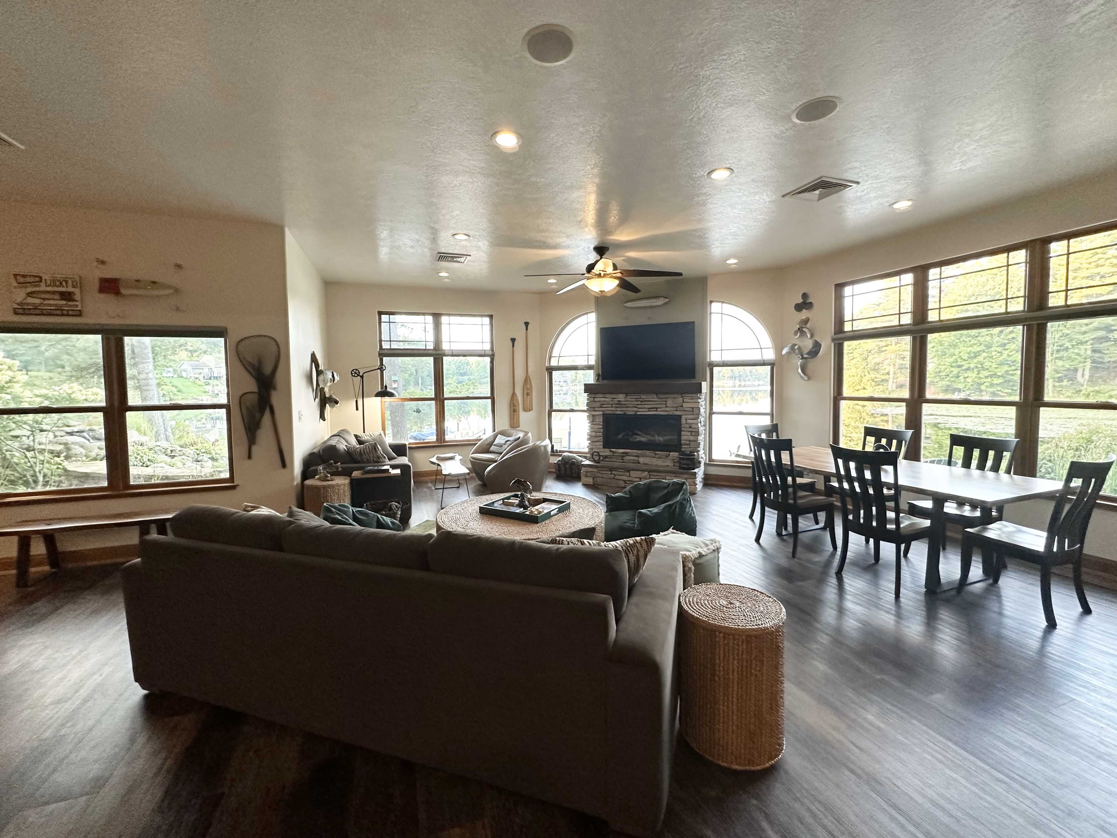 A spacious living area with a large window, a circular coffee table, a comfortable sofa, and a dining table with chairs.