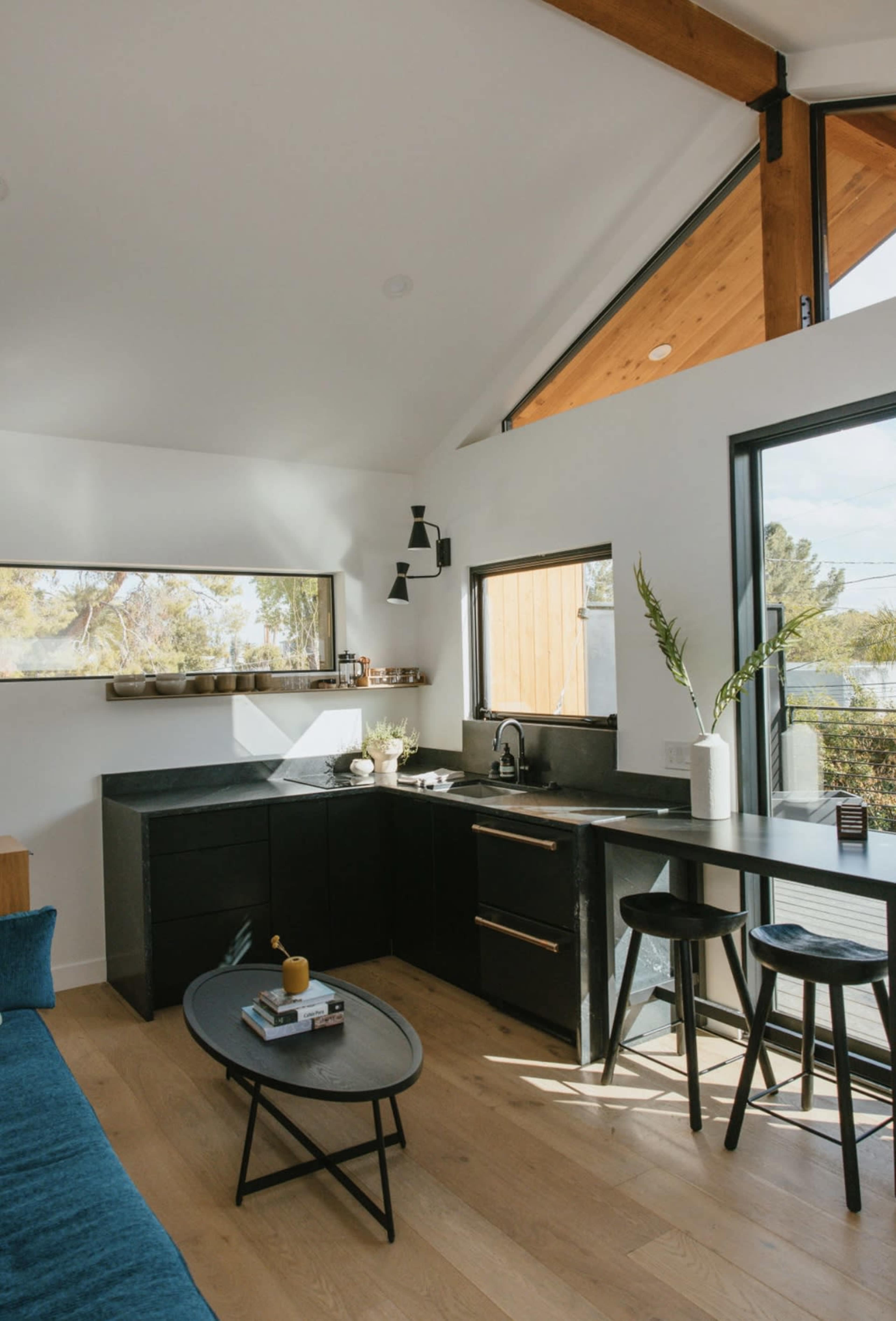 A modern kitchen nook with black cabinetry, a small dining table, and large windows allowing natural light to fill the space.