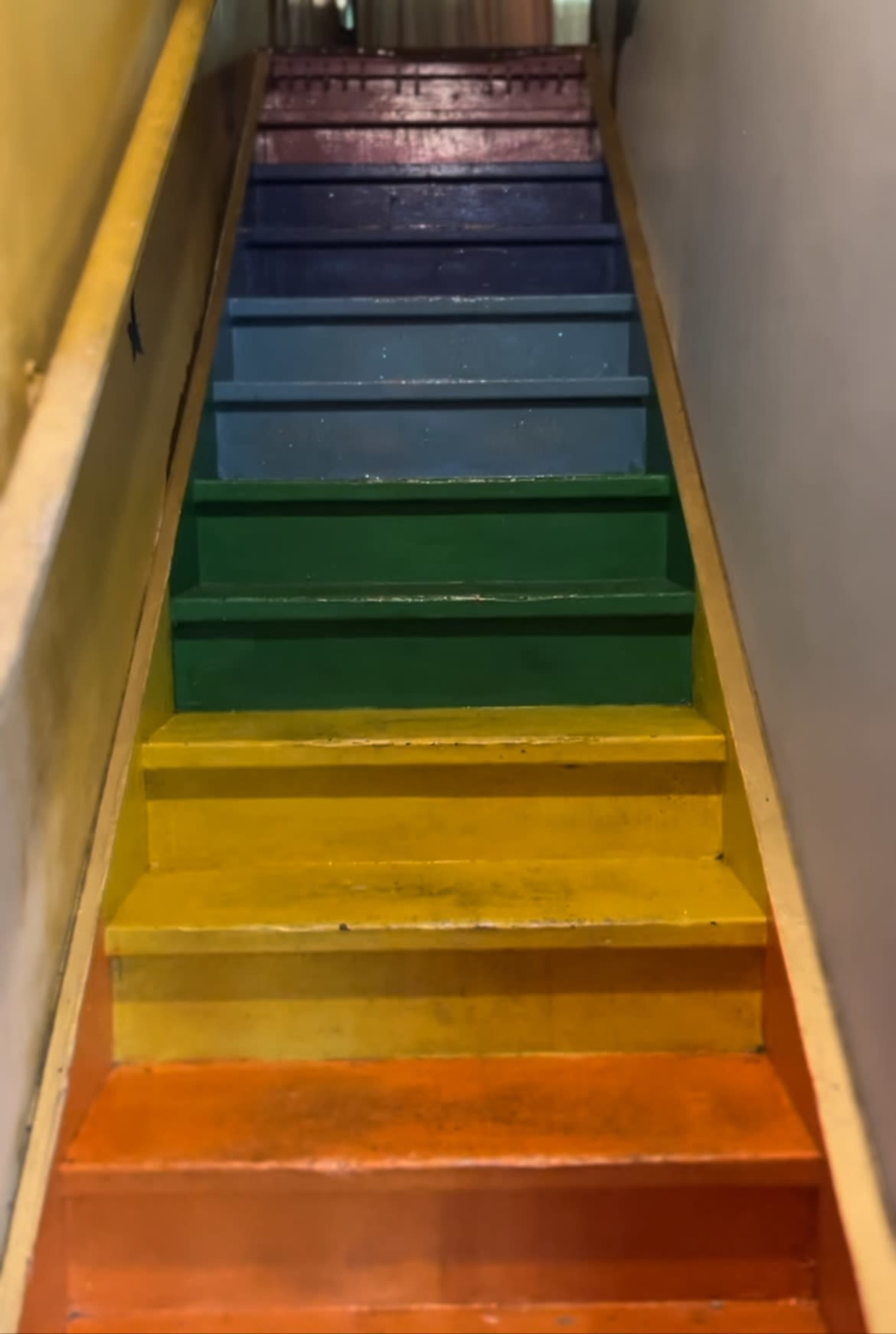 A staircase with steps painted in bright colors: orange, yellow, green, blue, and purple.