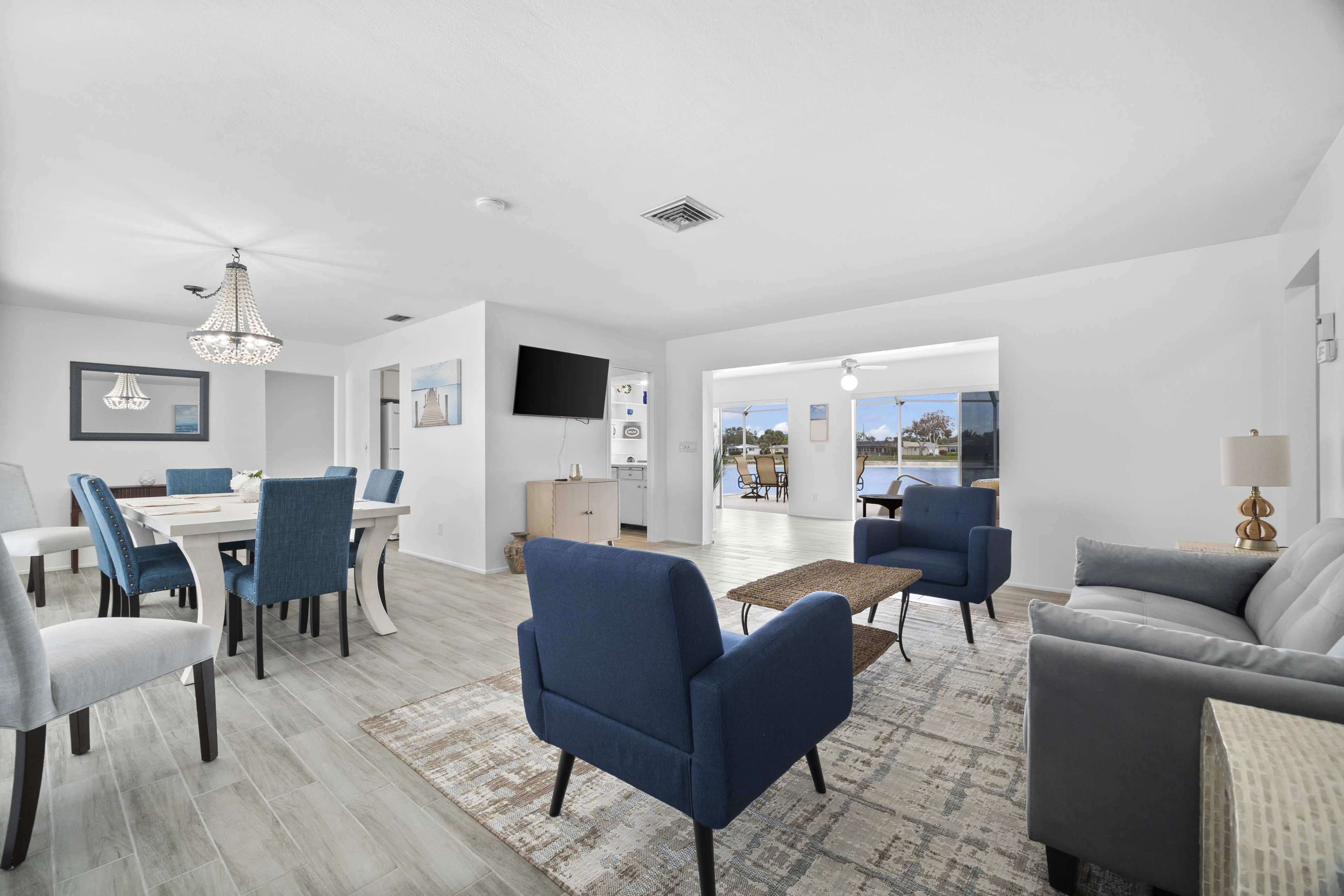 A bright, airy living space with a dining area, a seating arrangement, and large windows overlooking a body of water.