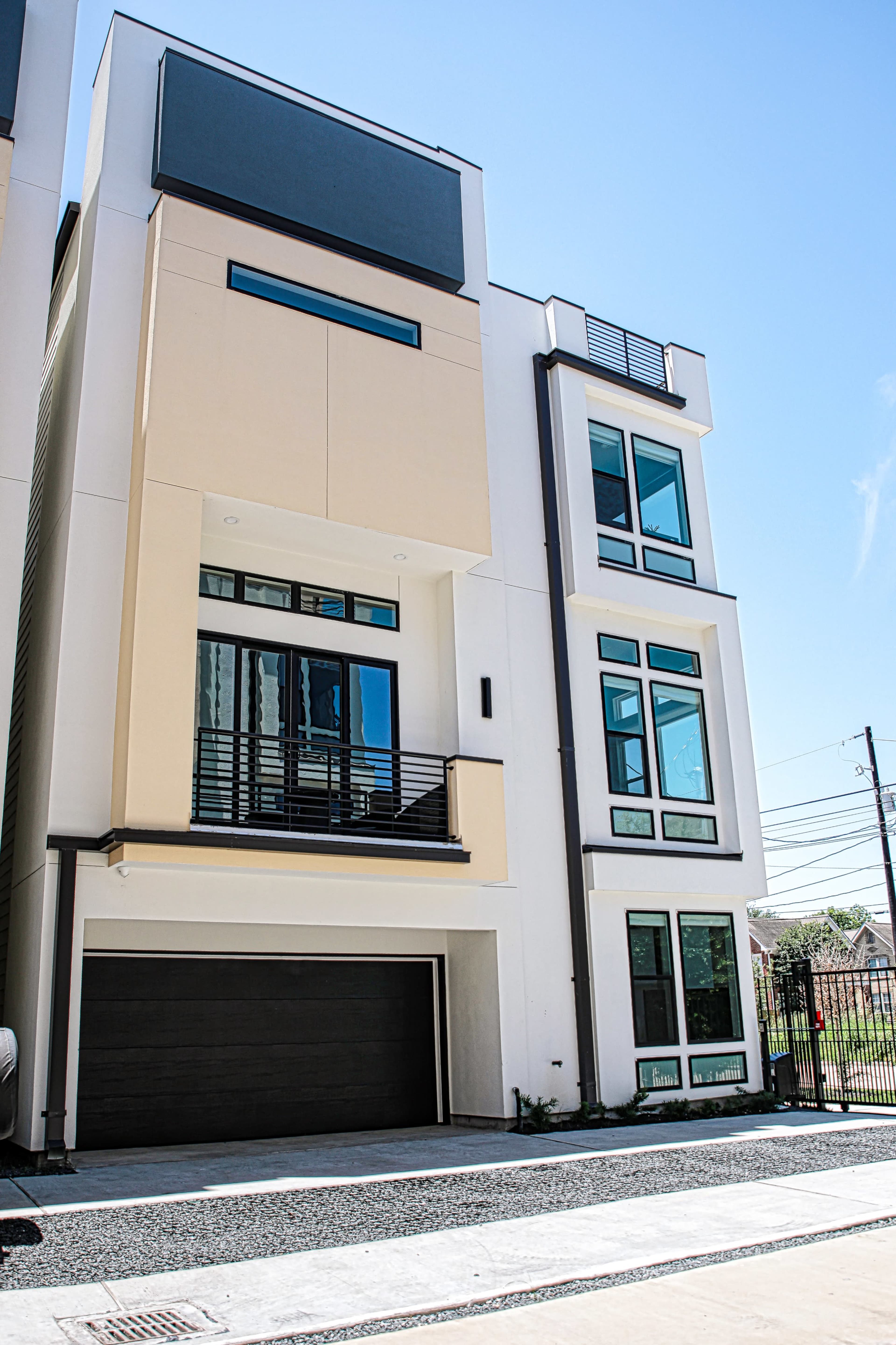 The image shows a modern three-story residential building with large windows and a two-car garage.