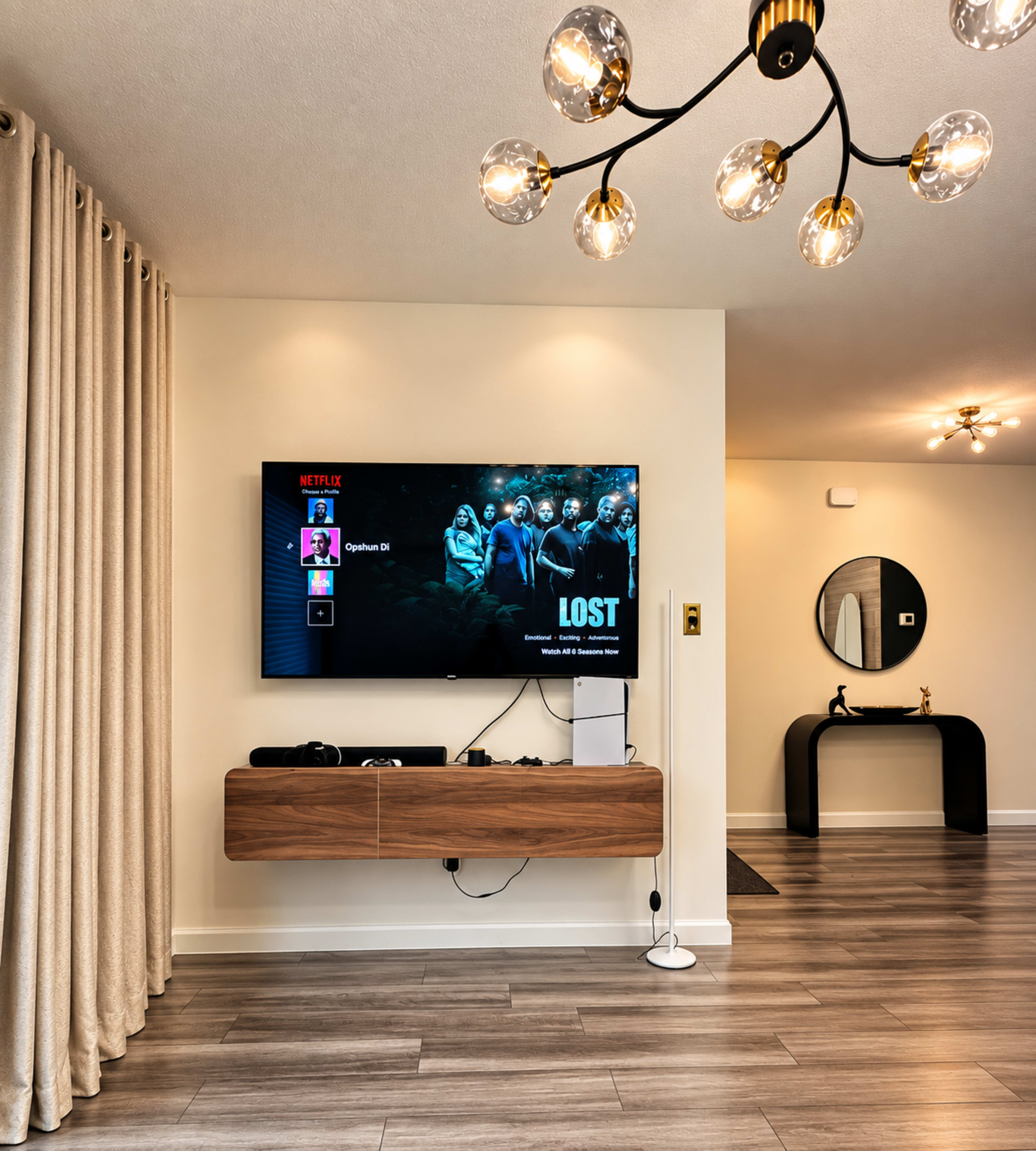 A modern living room features a wall-mounted television displaying a Netflix interface, with a wooden console beneath it and a chandelier overhead.