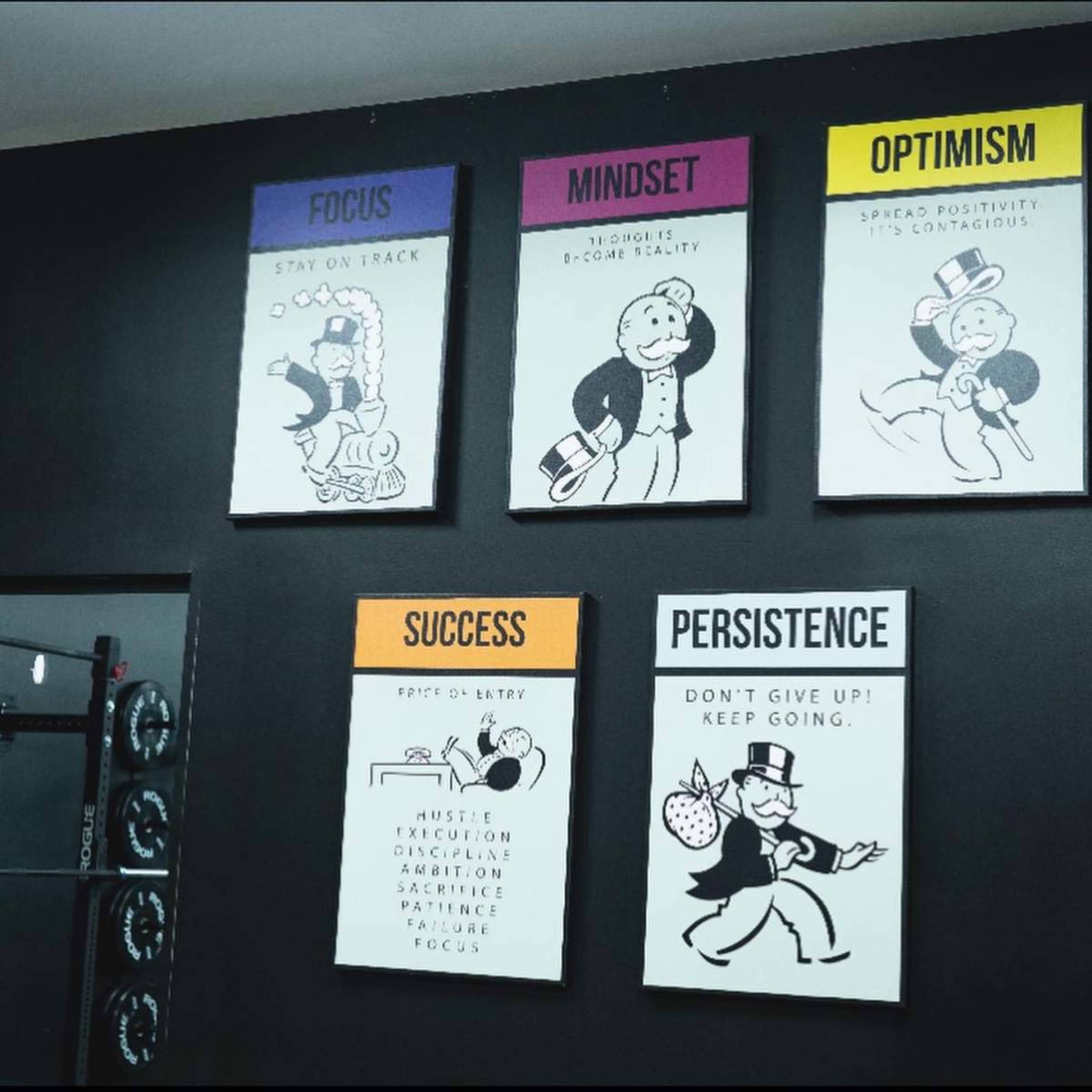 The image shows a wall adorned with five framed posters featuring motivational phrases along with illustrations of a cartoon character.