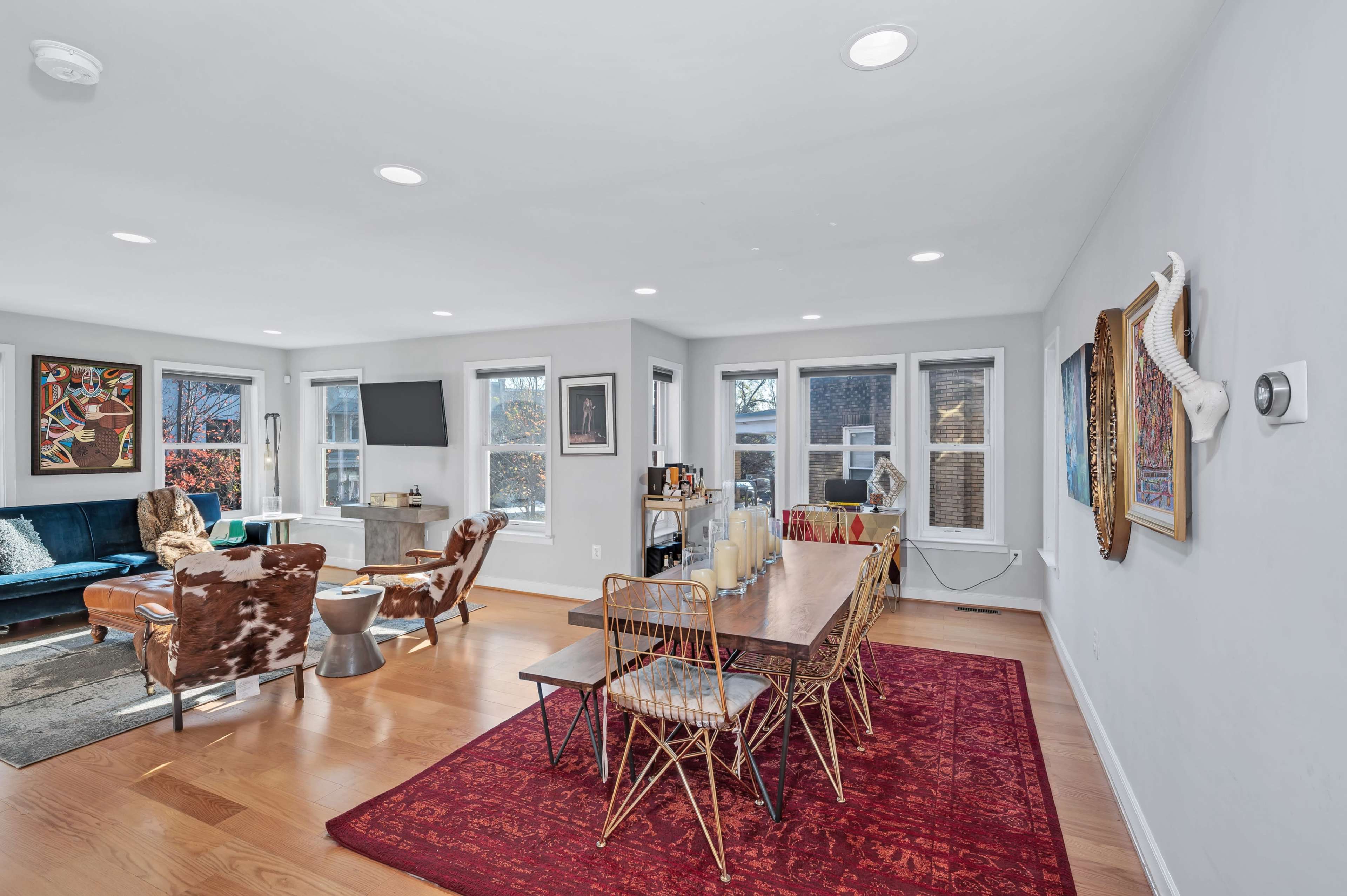 A bright, open living and dining area with a large table, chairs, and a mix of modern and eclectic décor.