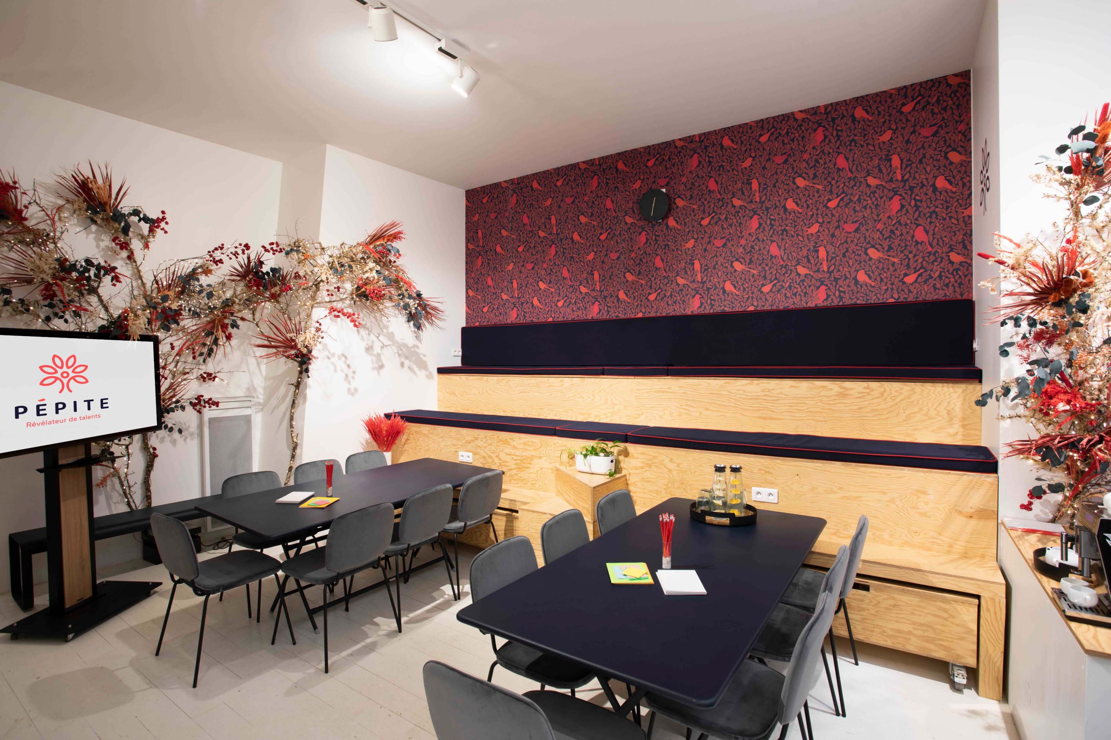 A meeting room with wooden seating, dark tables, and a decorative wall featuring a red floral pattern.