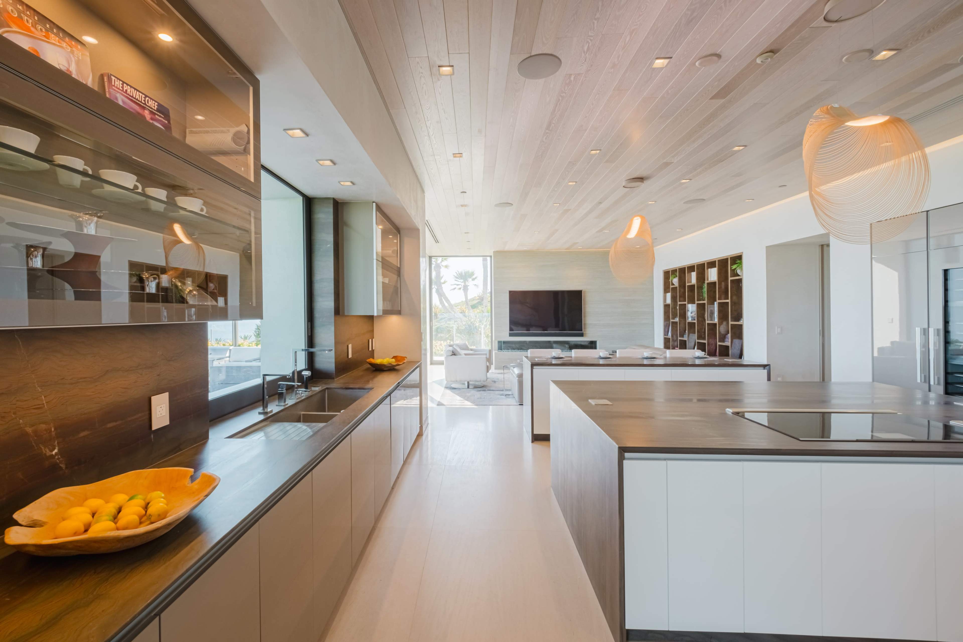 A modern kitchen featuring sleek cabinetry, a central island, and large windows that provide ample natural light.