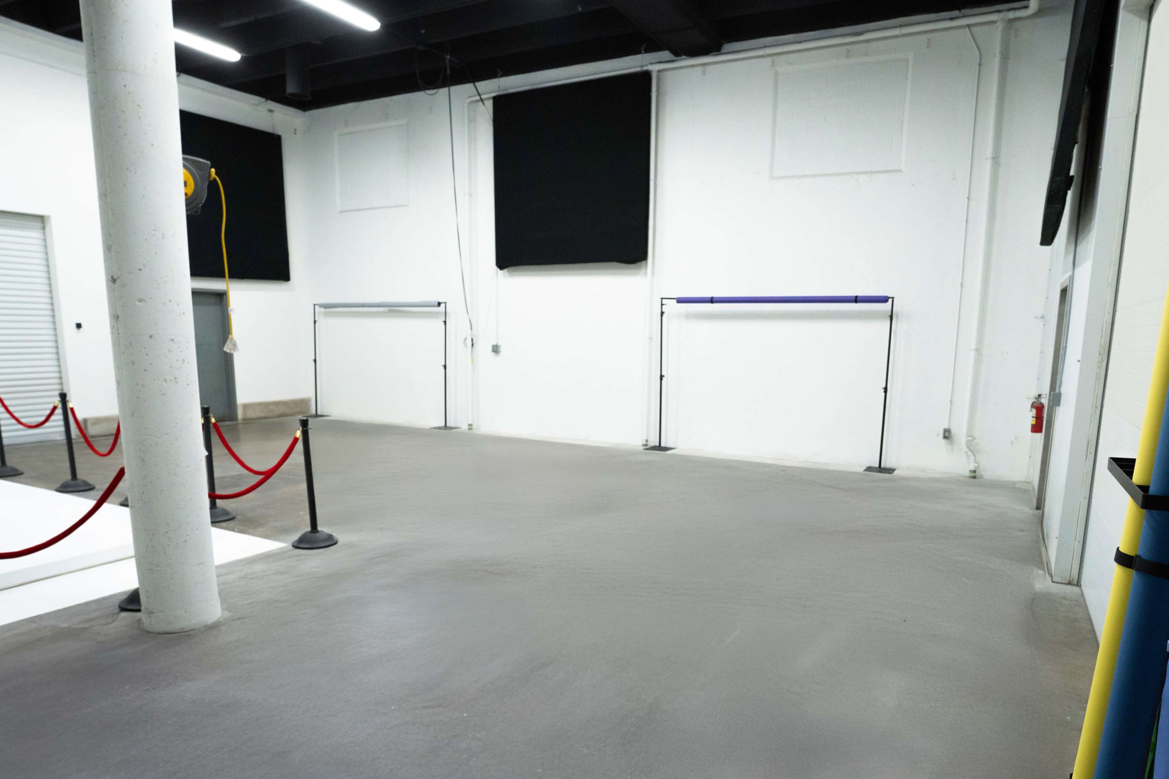 The image shows an empty indoor space with a smooth concrete floor, gray walls, and two stands on opposite sides.