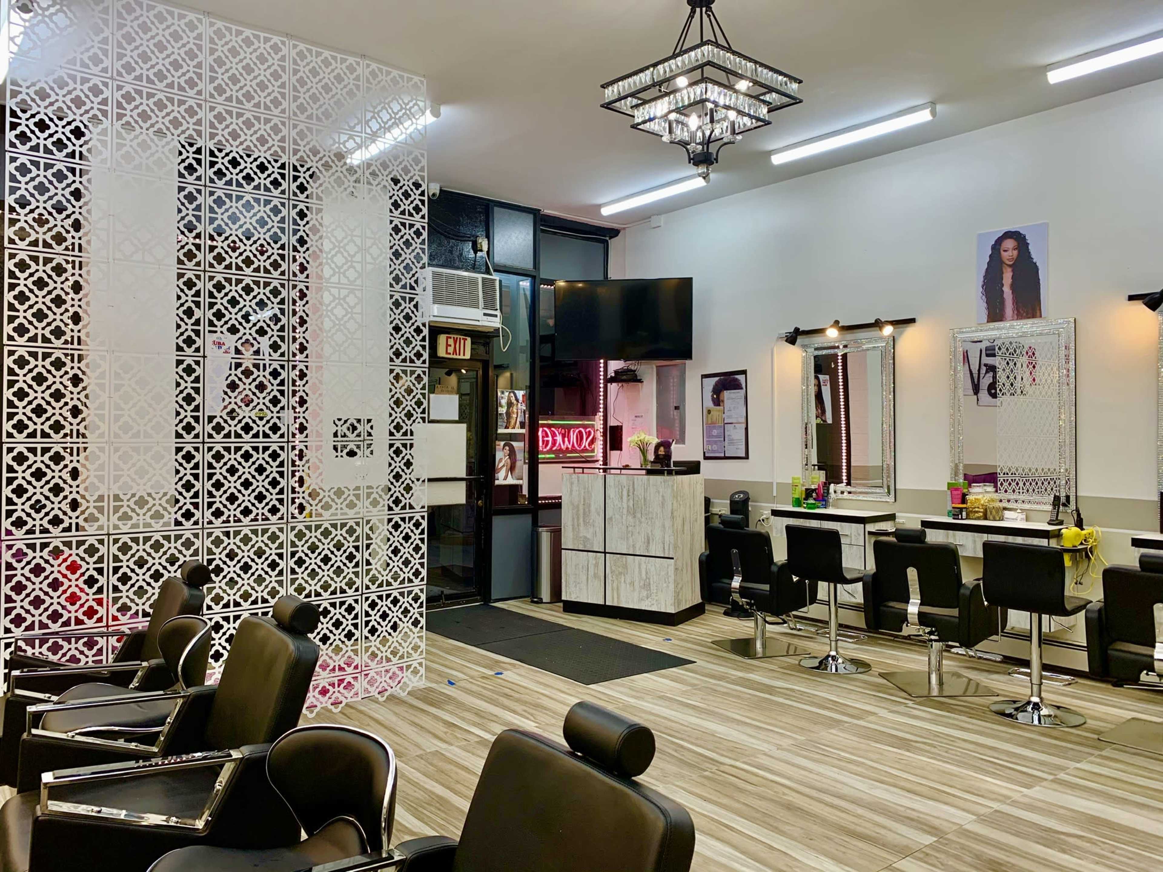 A modern hair salon with black styling chairs, mirrored stations, and decorative partition screens.