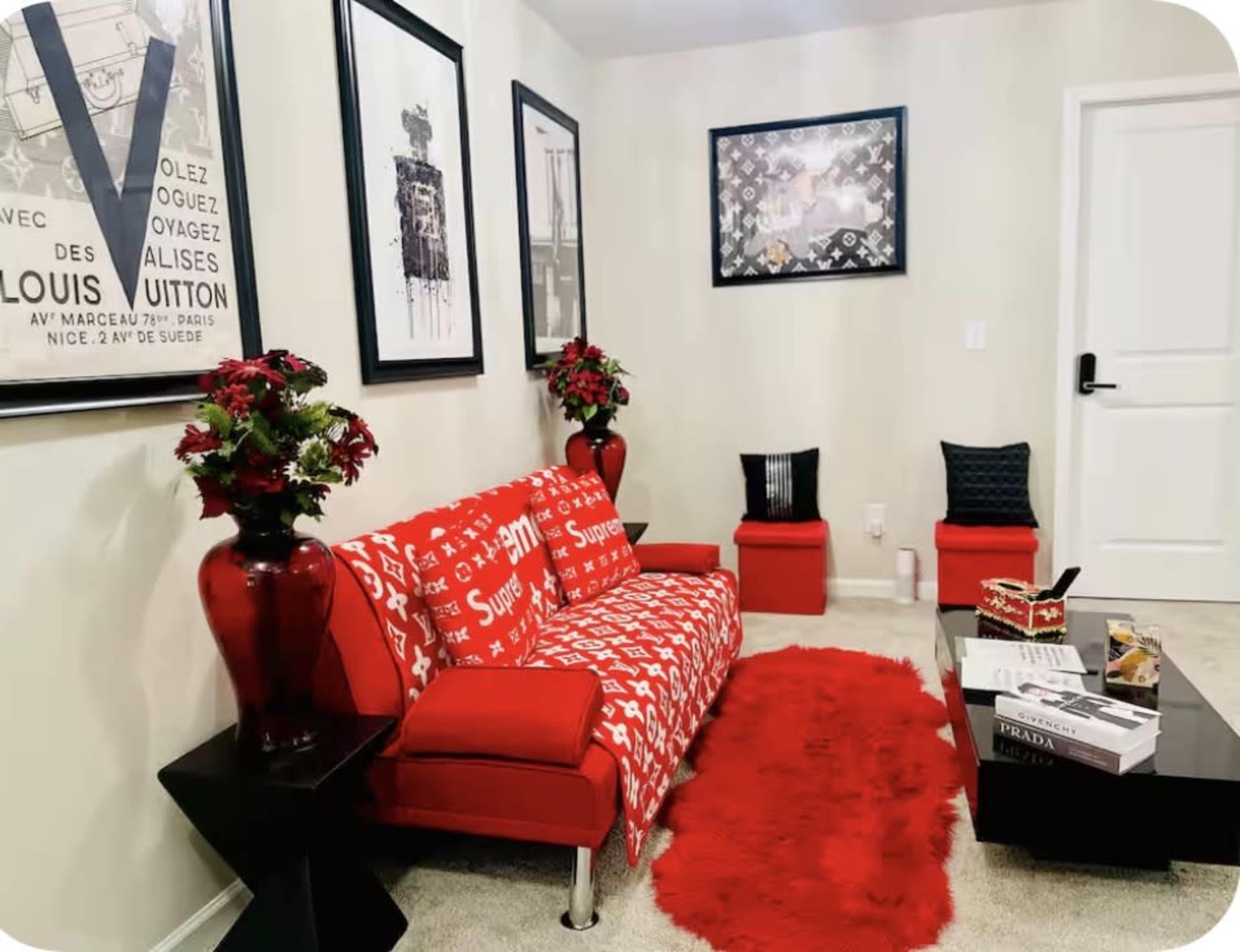The image features a modern living room with a red sofa adorned with a patterned throw, surrounded by decorative art pieces and a black coffee table.