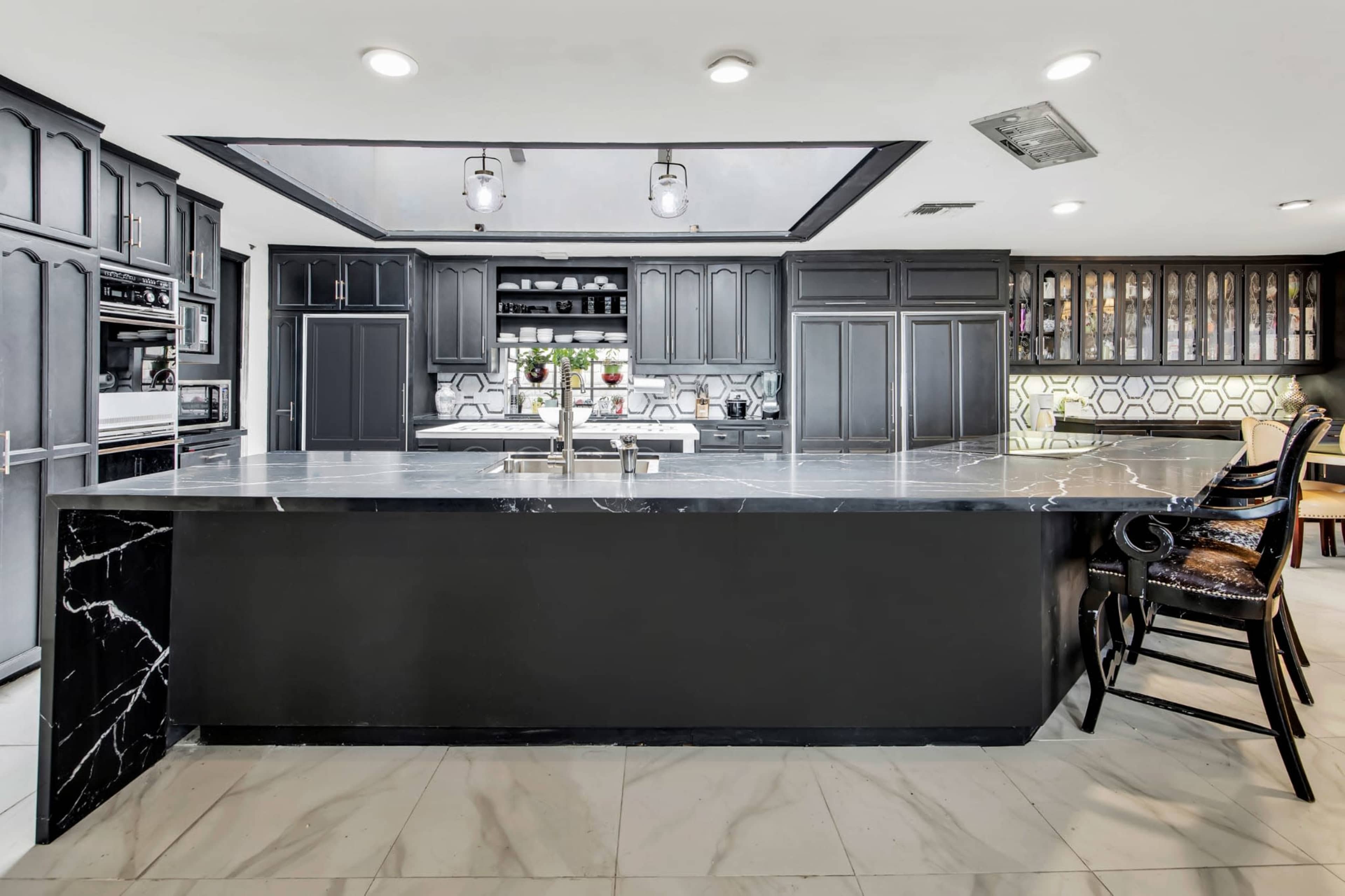The kitchen features a large black island with a marble countertop, black cabinetry, and modern appliances.