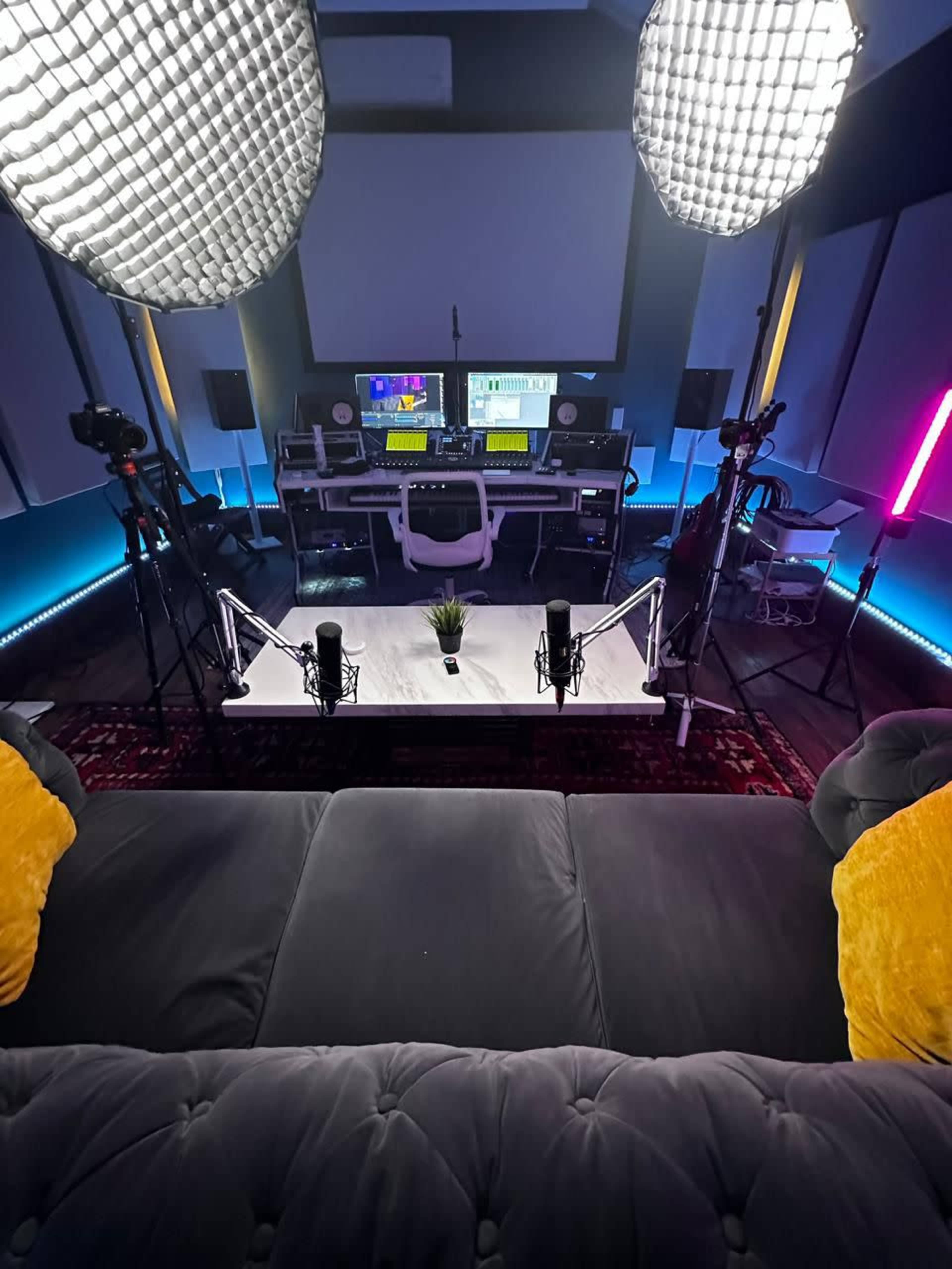 A modern recording studio featuring sound equipment, cameras, and large lights in a dimly lit room.