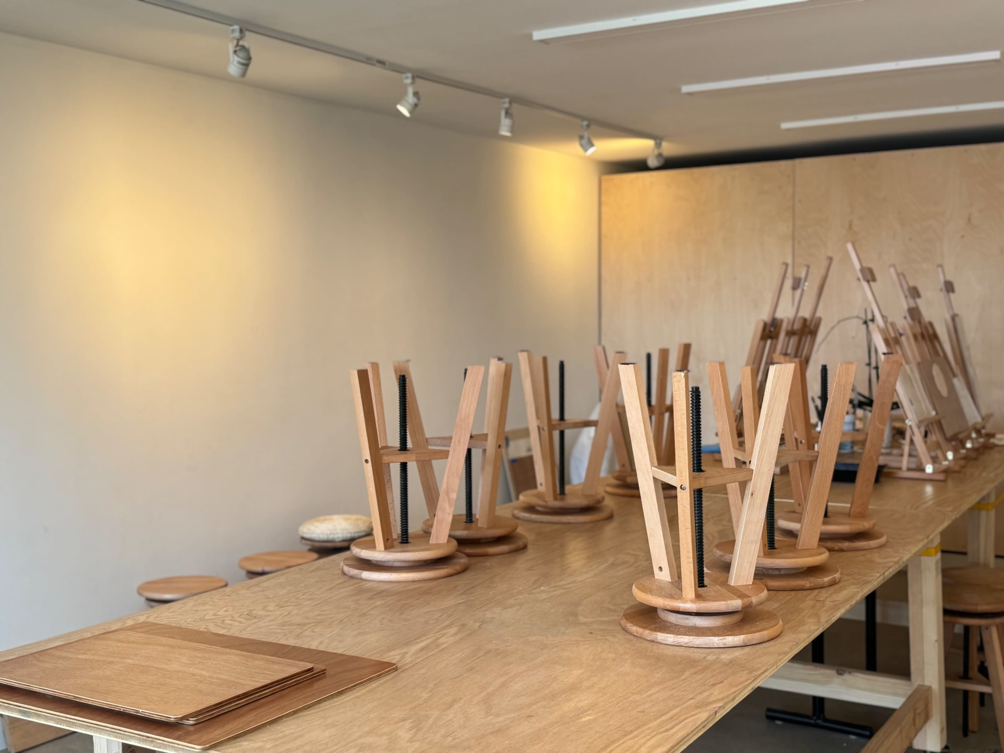 The image shows a workshop space with several wooden tables and chairs, all positioned upside down on the tables.
