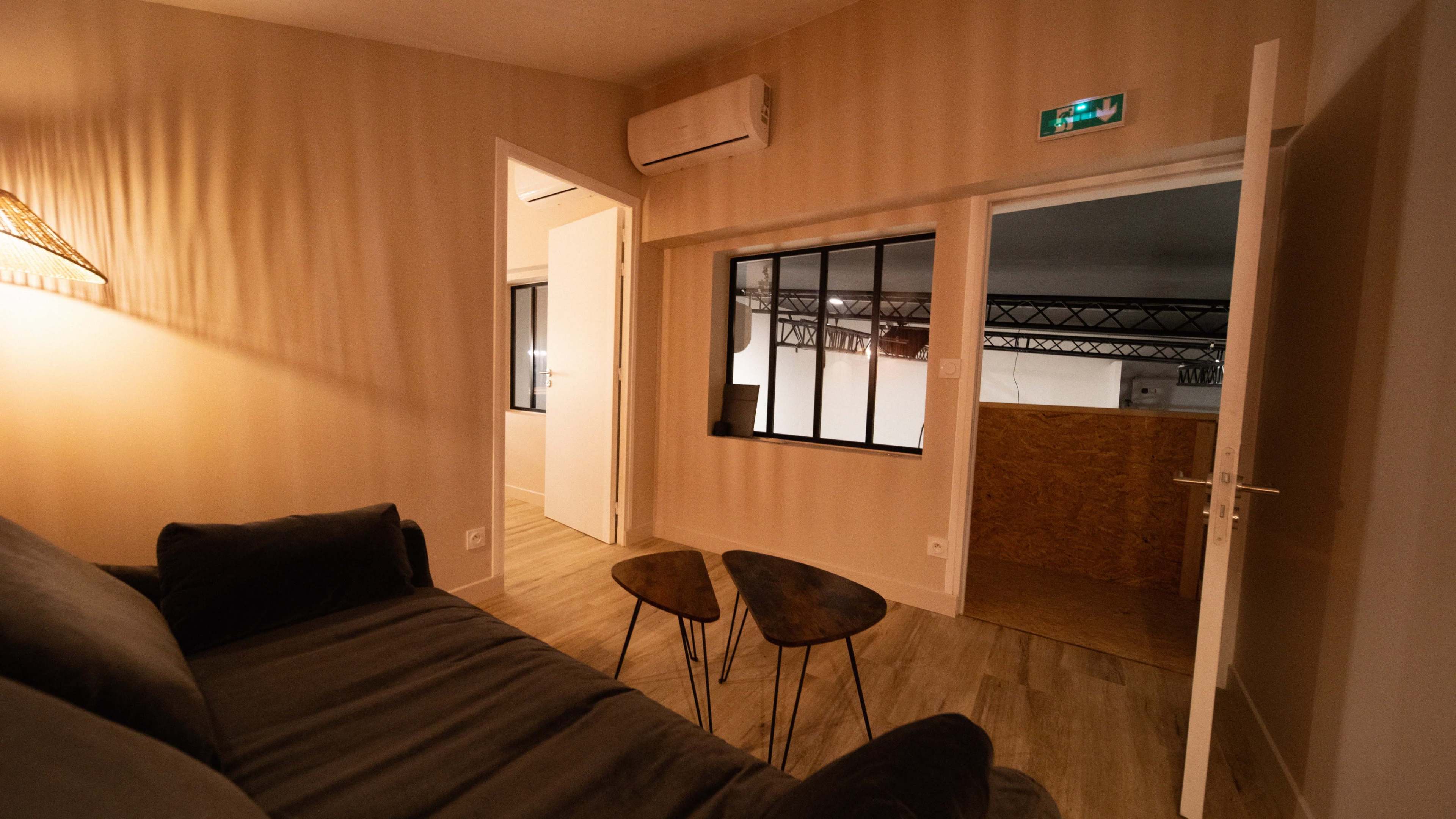 A modern interior space with a sofa, two small tables, and an open doorway leading to another room.