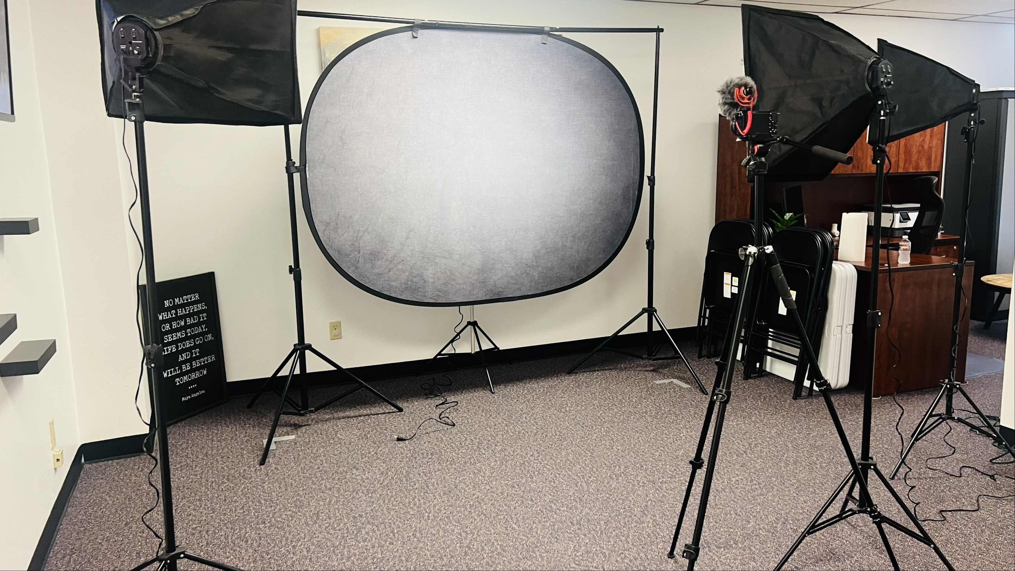 The image shows a photography setup featuring a backdrop, two softbox lights, and tripods in an indoor space.