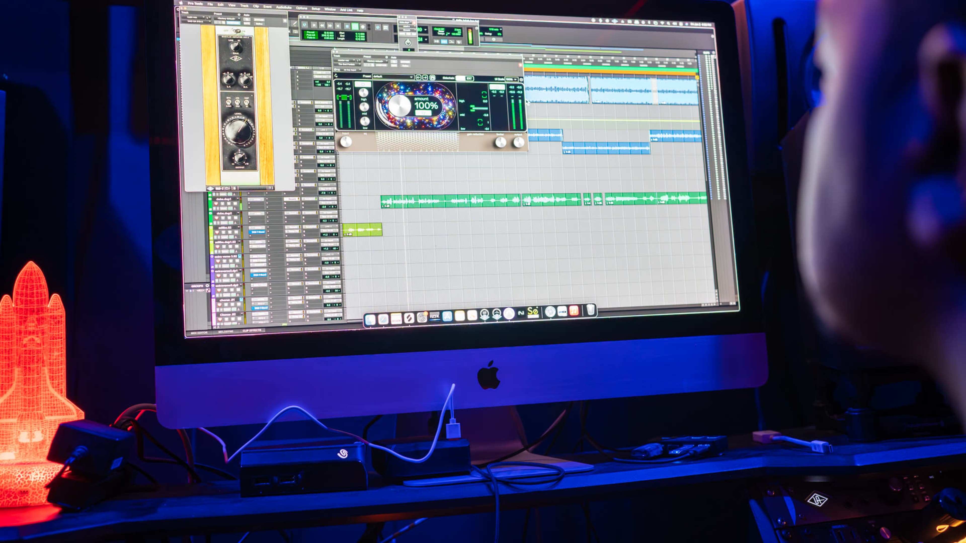 A computer screen displaying a music production software interface is shown with various audio tracks layered on a timeline.