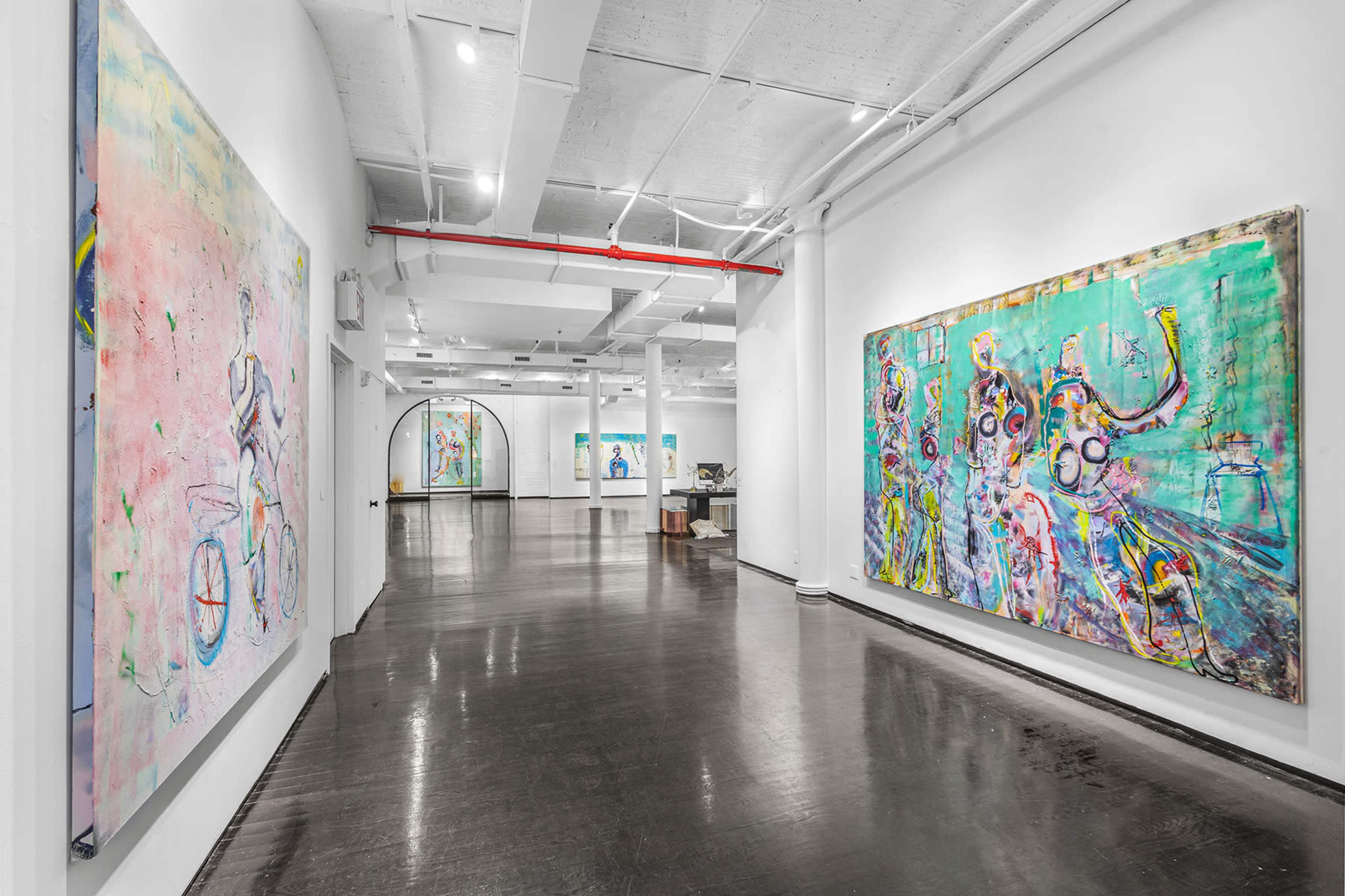 A spacious contemporary art gallery with large colorful abstract paintings displayed on the white walls and polished black flooring.