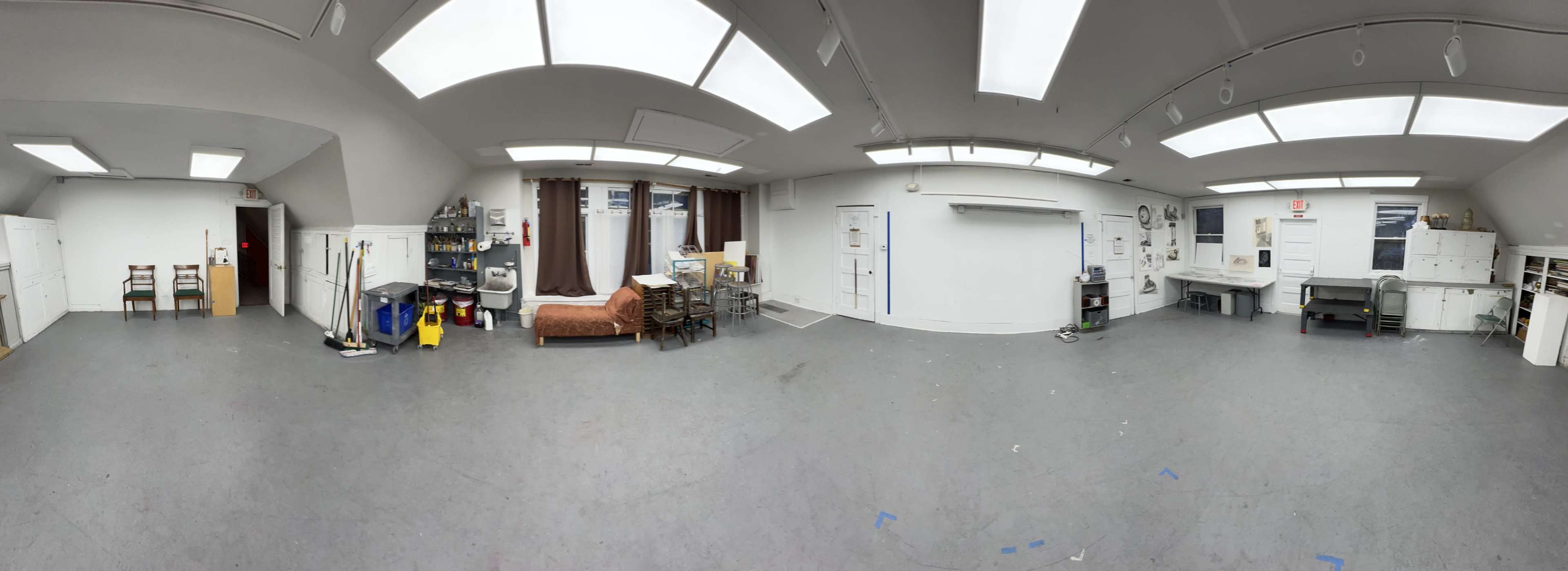 A spacious, well-lit room with various furniture pieces, storage cabinets, and a work area.
