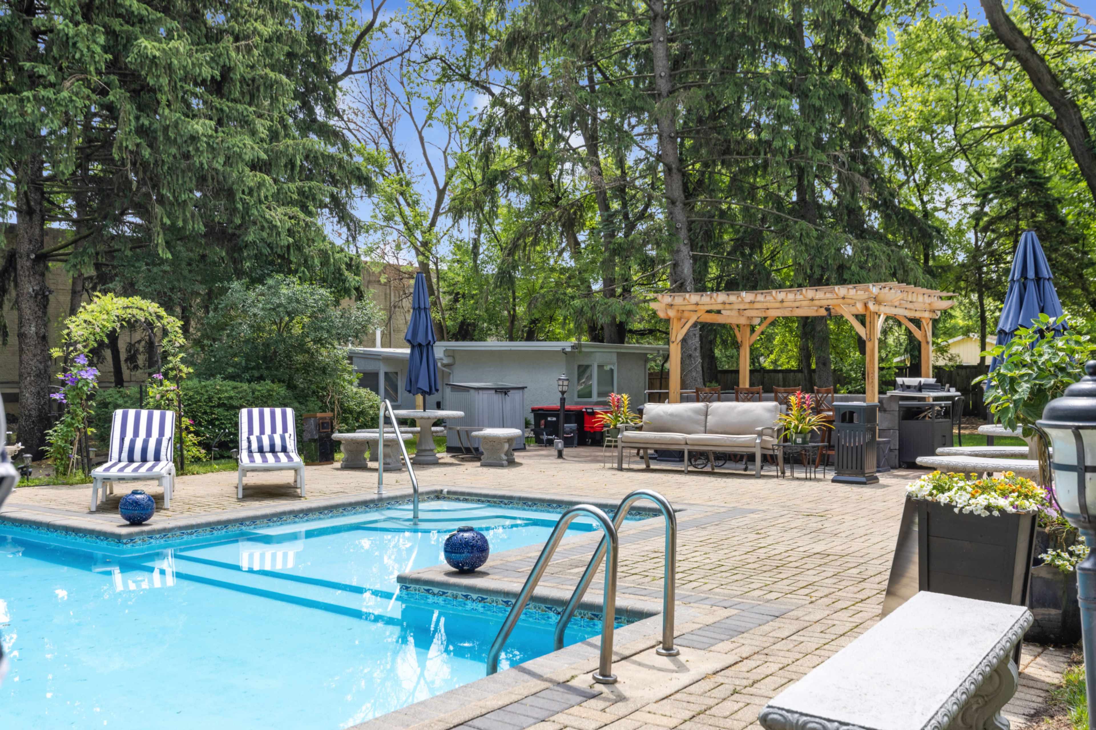 The image shows a backyard pool area with lounge chairs, a gazebo, and lush green trees surrounding the space.