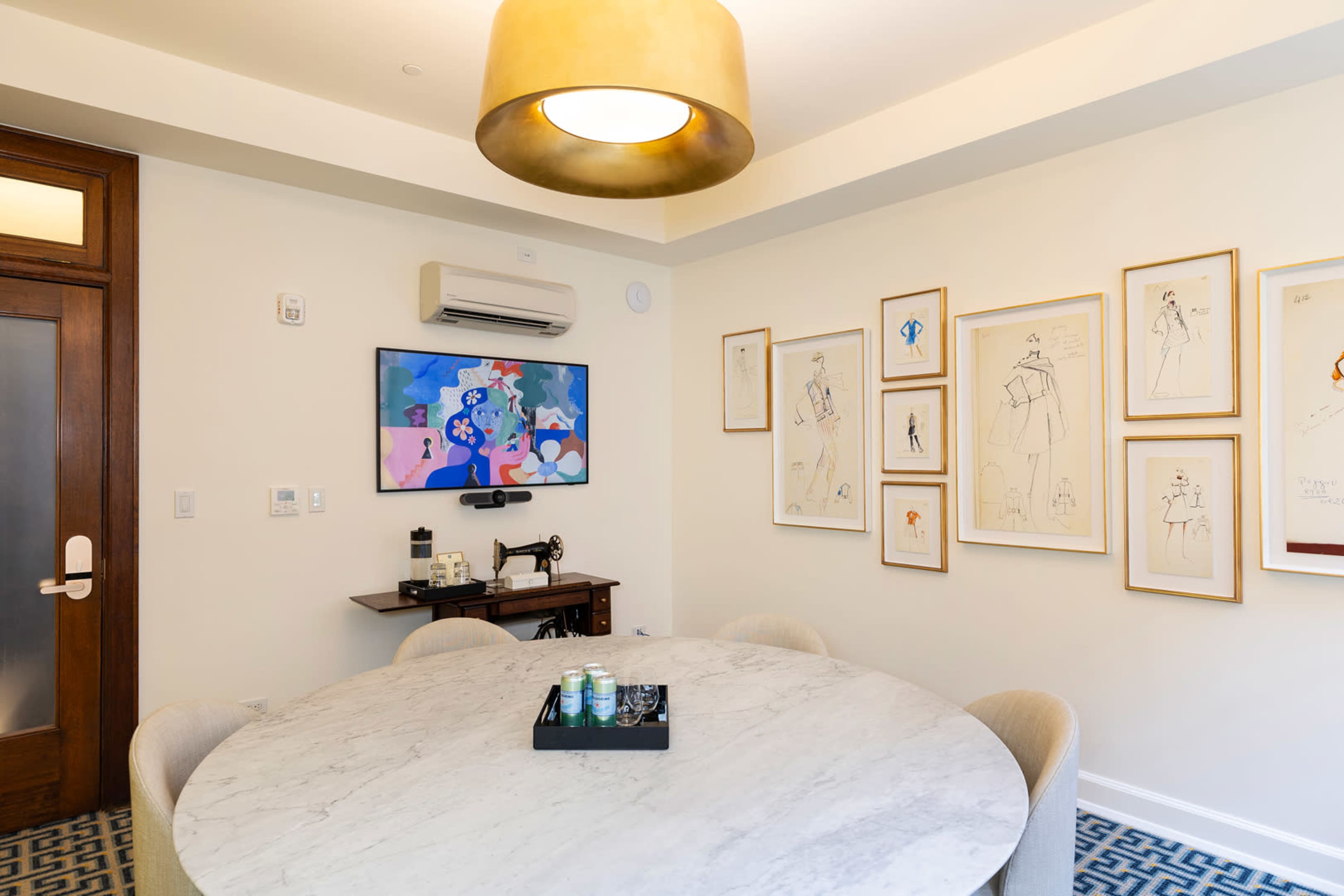 A dining area featuring a round marble table, a light fixture overhead, and framed artwork on the walls.