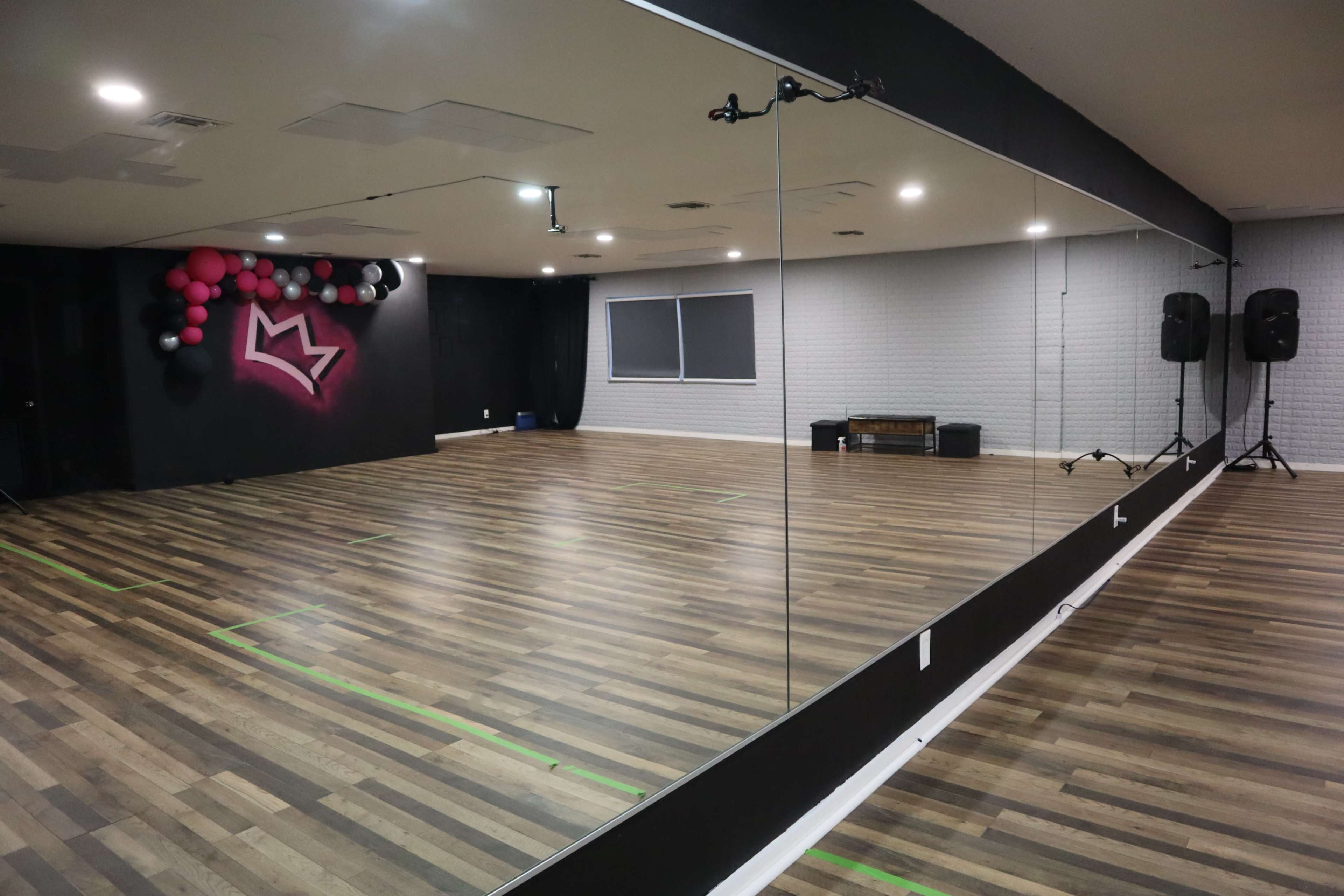 A dance studio featuring a mirrored wall, hardwood floors, and a balloon decoration in the corner.
