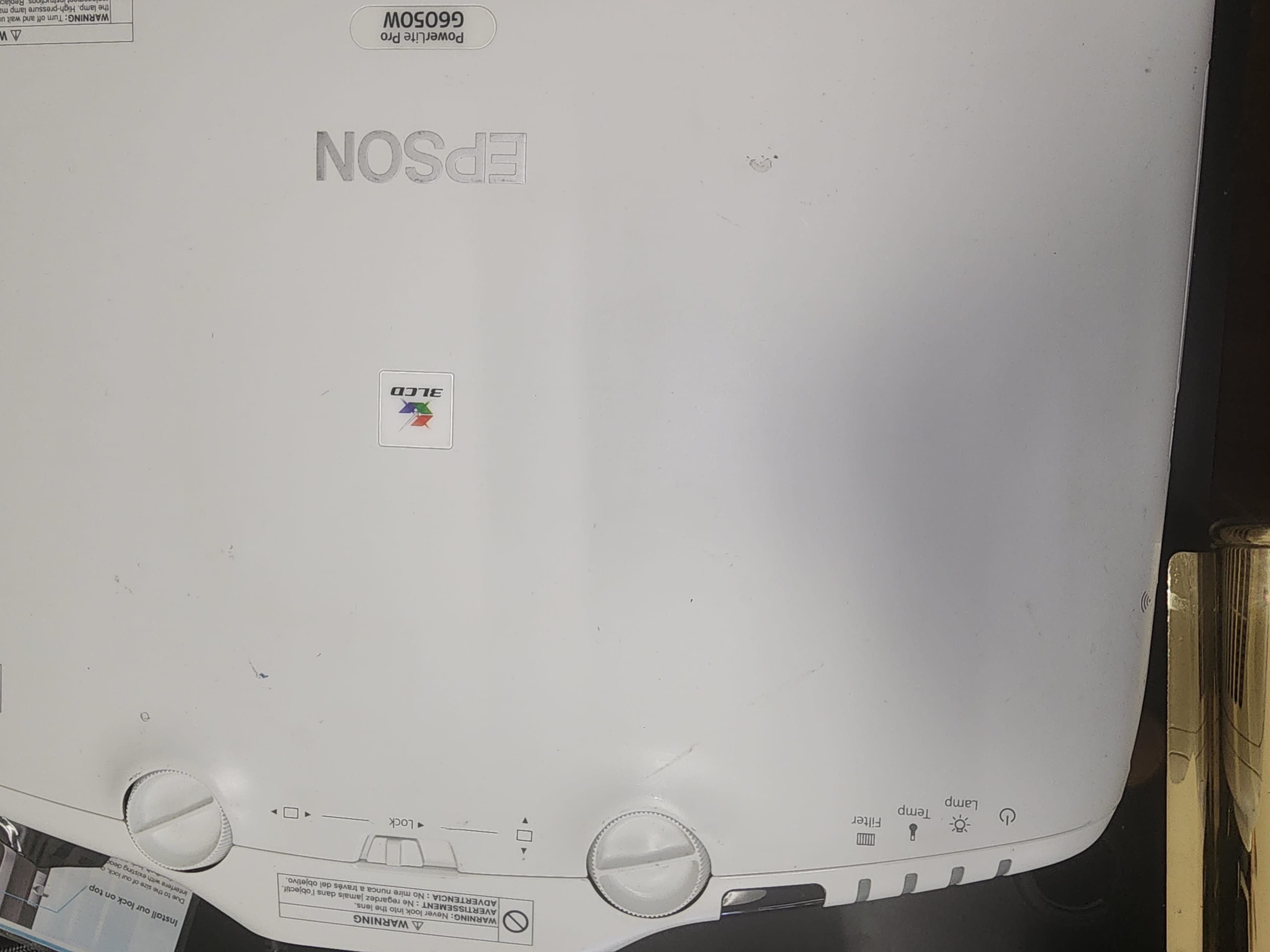 The image shows the top view of an Epson projector with control buttons and a brand logo.