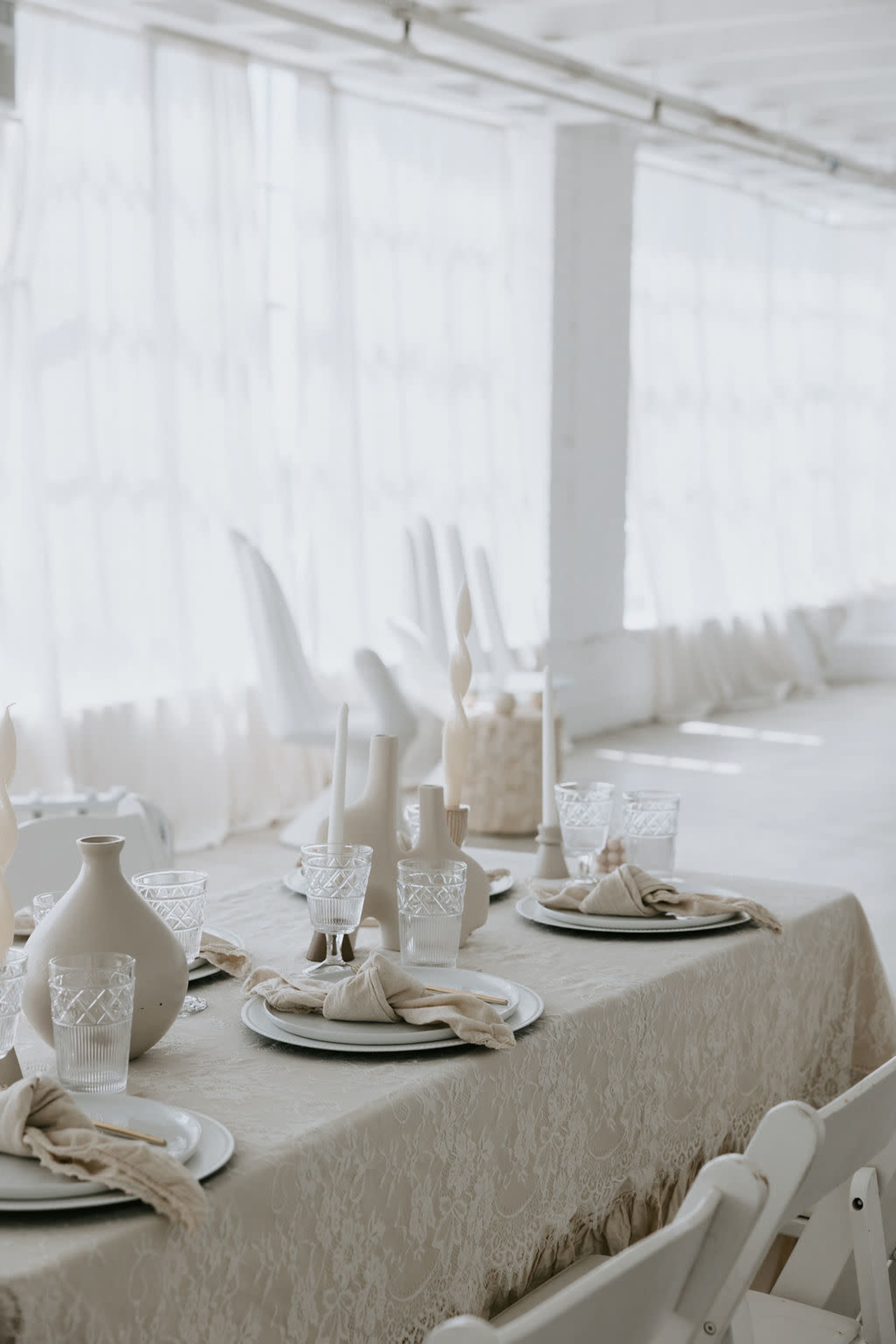 A elegantly set dining table with plates, glassware, and decorative elements in a bright, airy room.