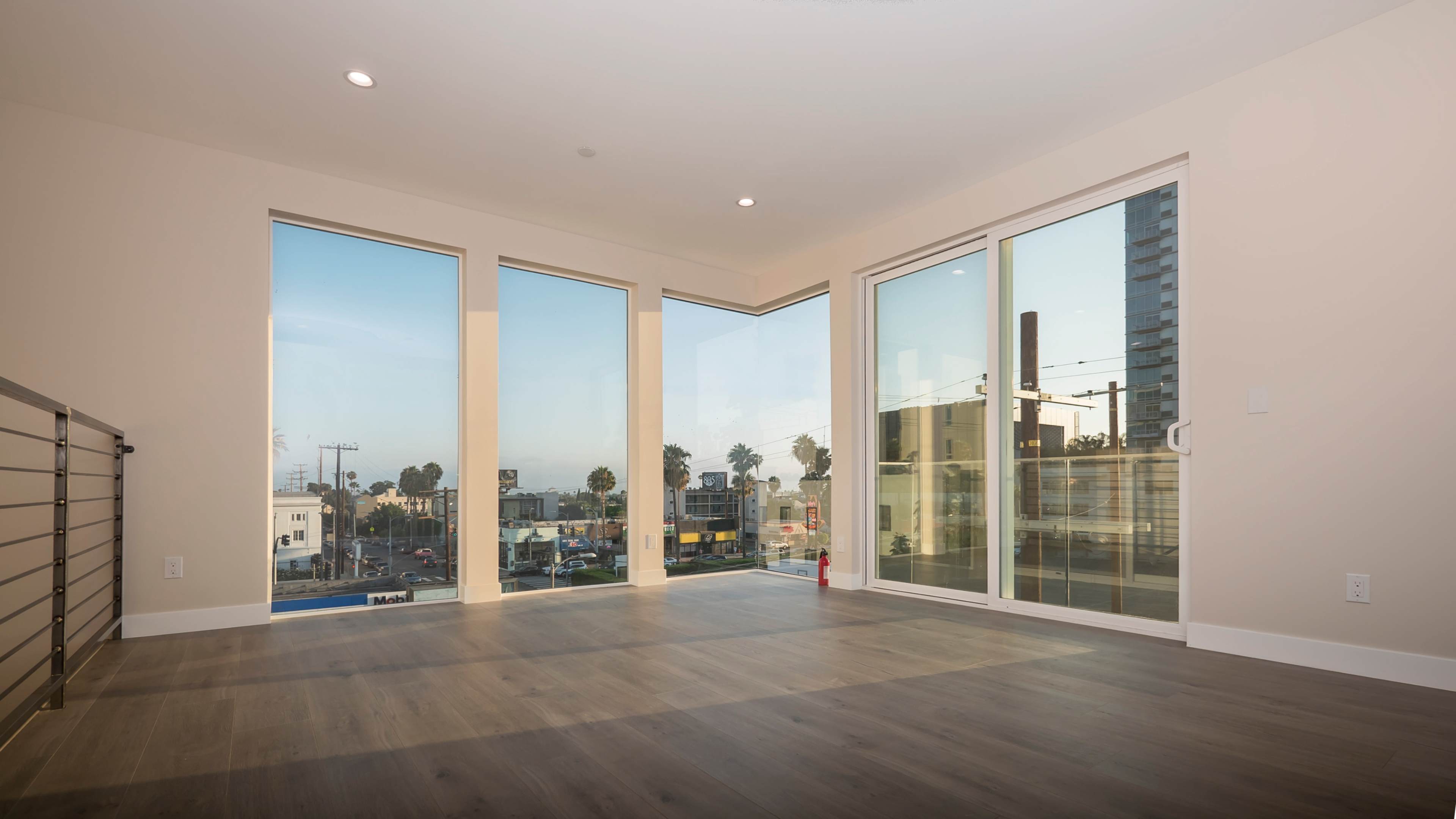 A modern, empty room with large windows providing a view of a street and buildings outside.
