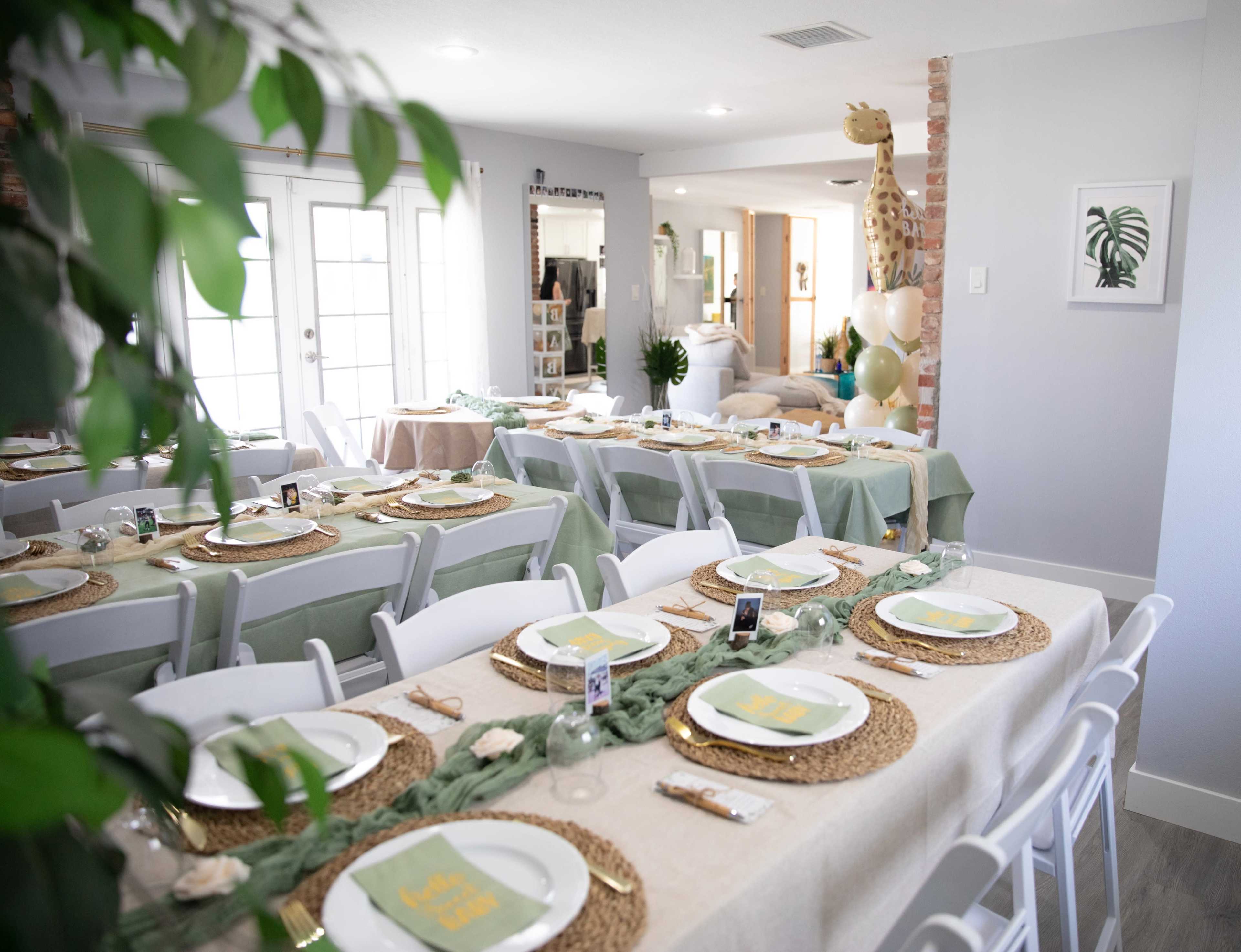 A dining area is set with multiple tables adorned with plates, napkins, and decorative centerpieces.