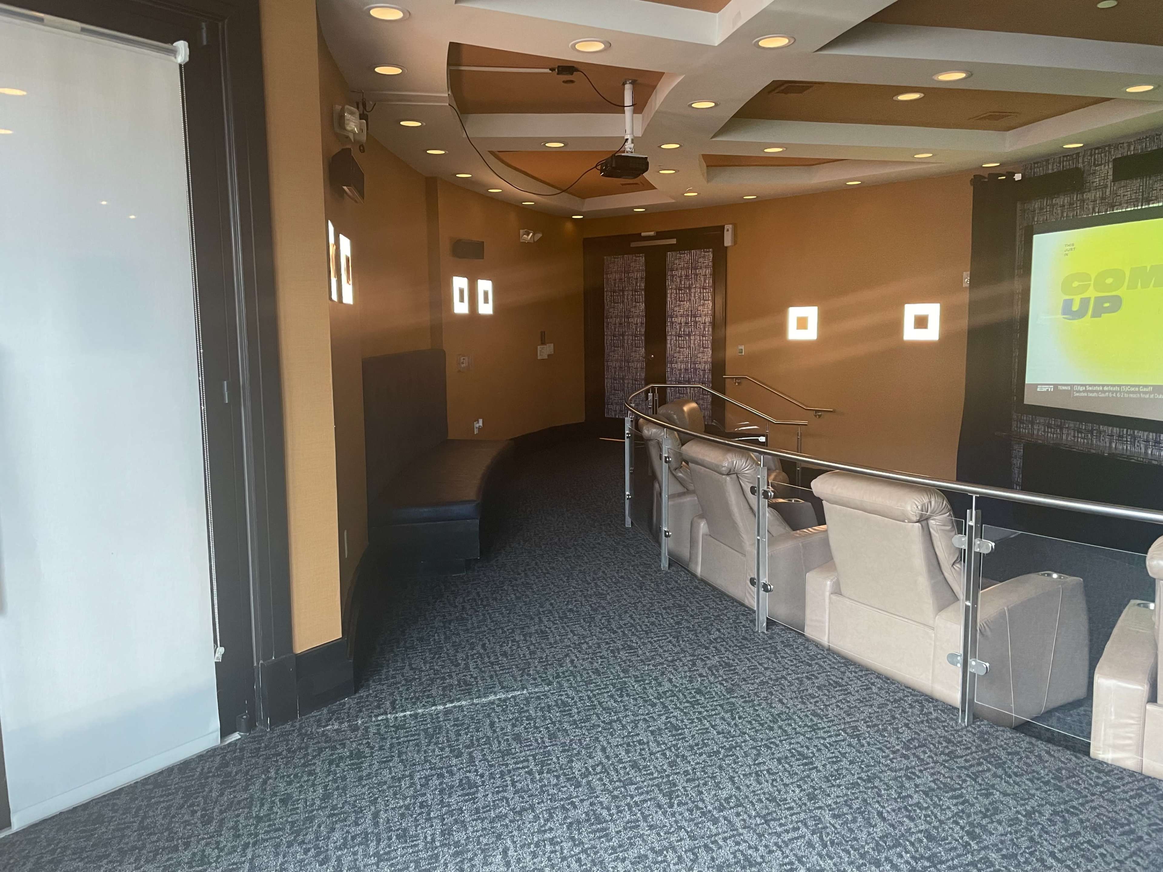 A hallway leading to a small theater-like room with plush chairs and a projector screen.