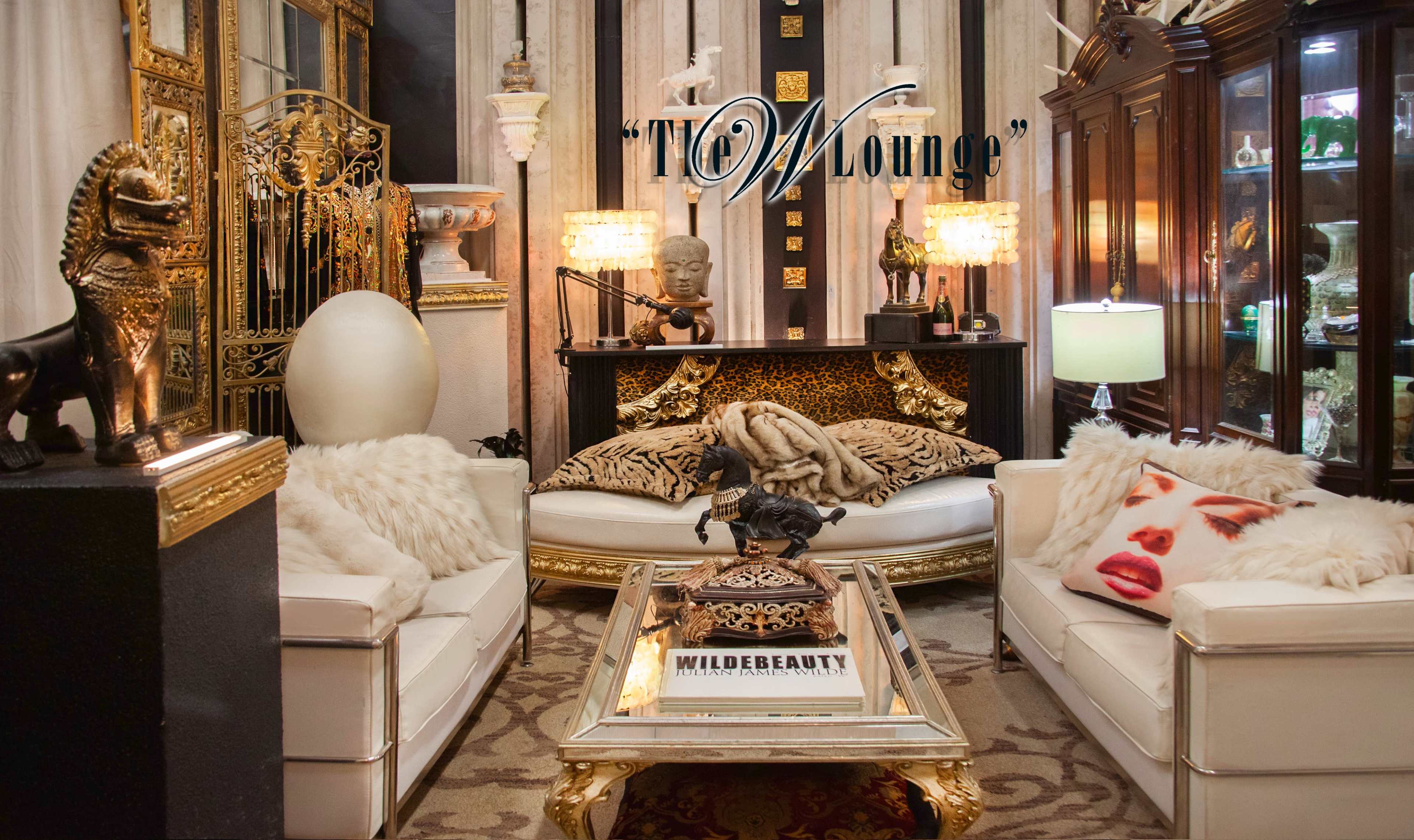 The image shows a stylish lounge area featuring white furniture, a glass coffee table, decorative sculptures, and a prominently displayed sign that reads "TOW Lounge."