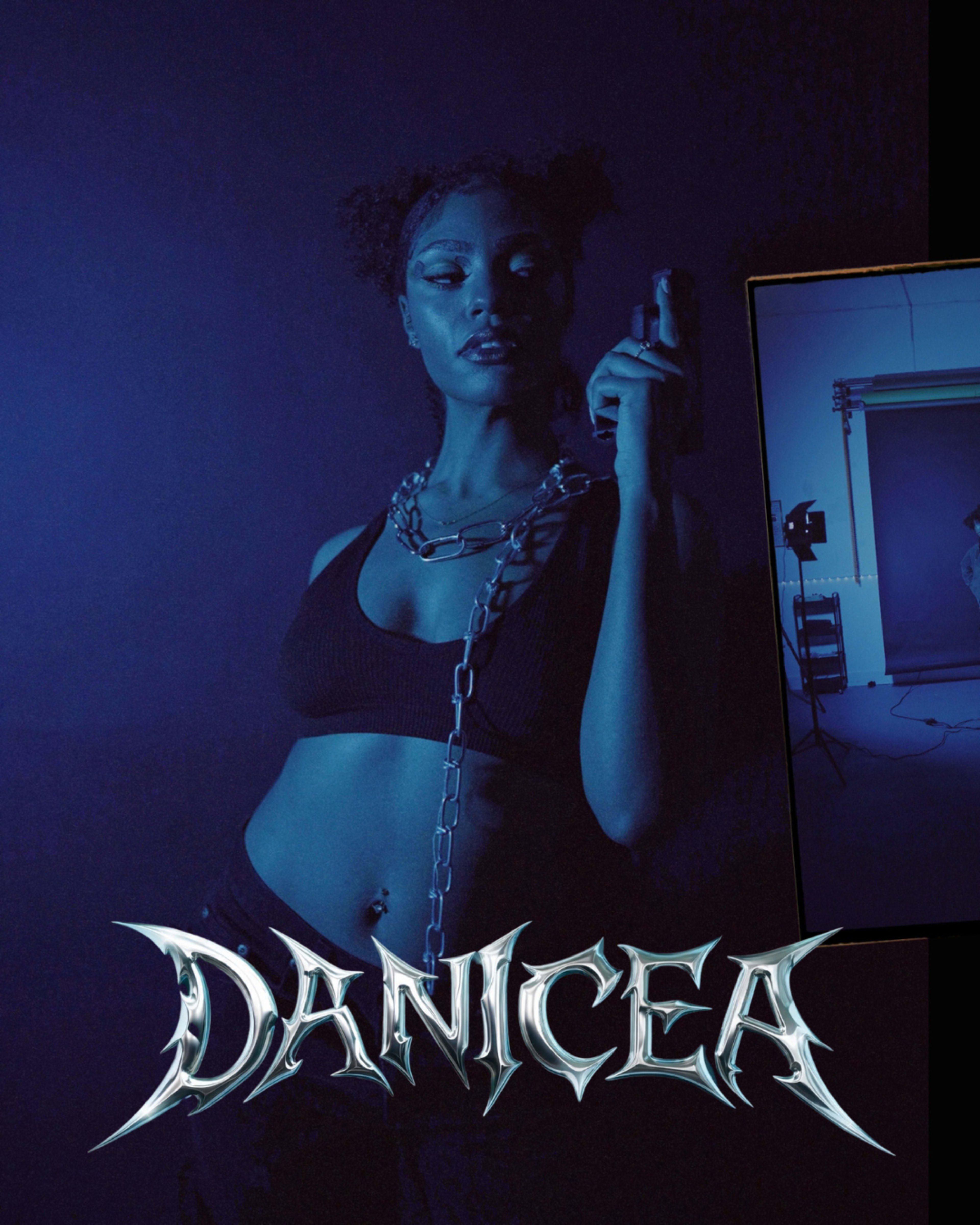 A woman poses dramatically in a dark, blue-lit setting, holding a gun and wearing a chain around her neck.