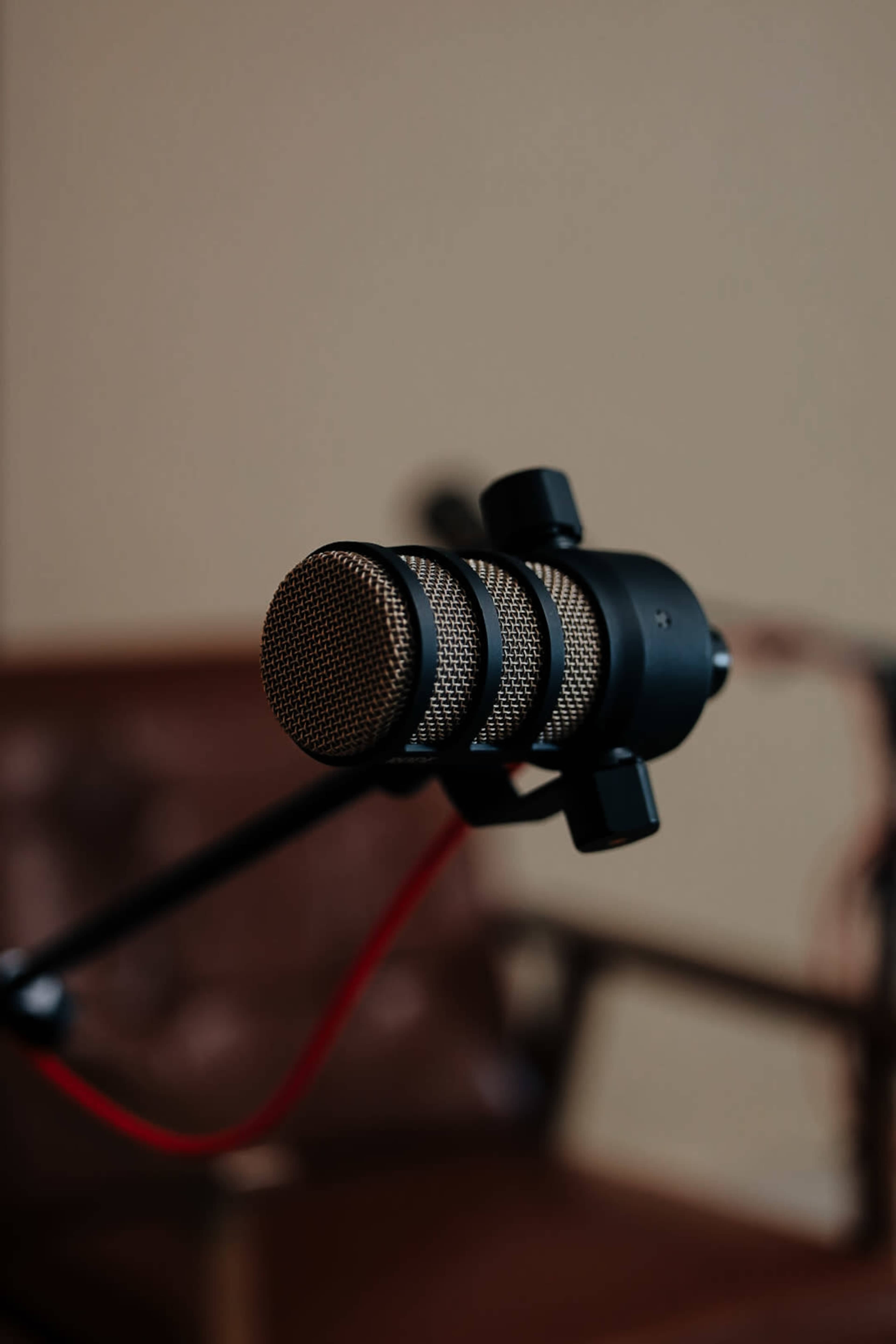 A close-up of a black microphone with a textured front, positioned in front of a brown chair.
