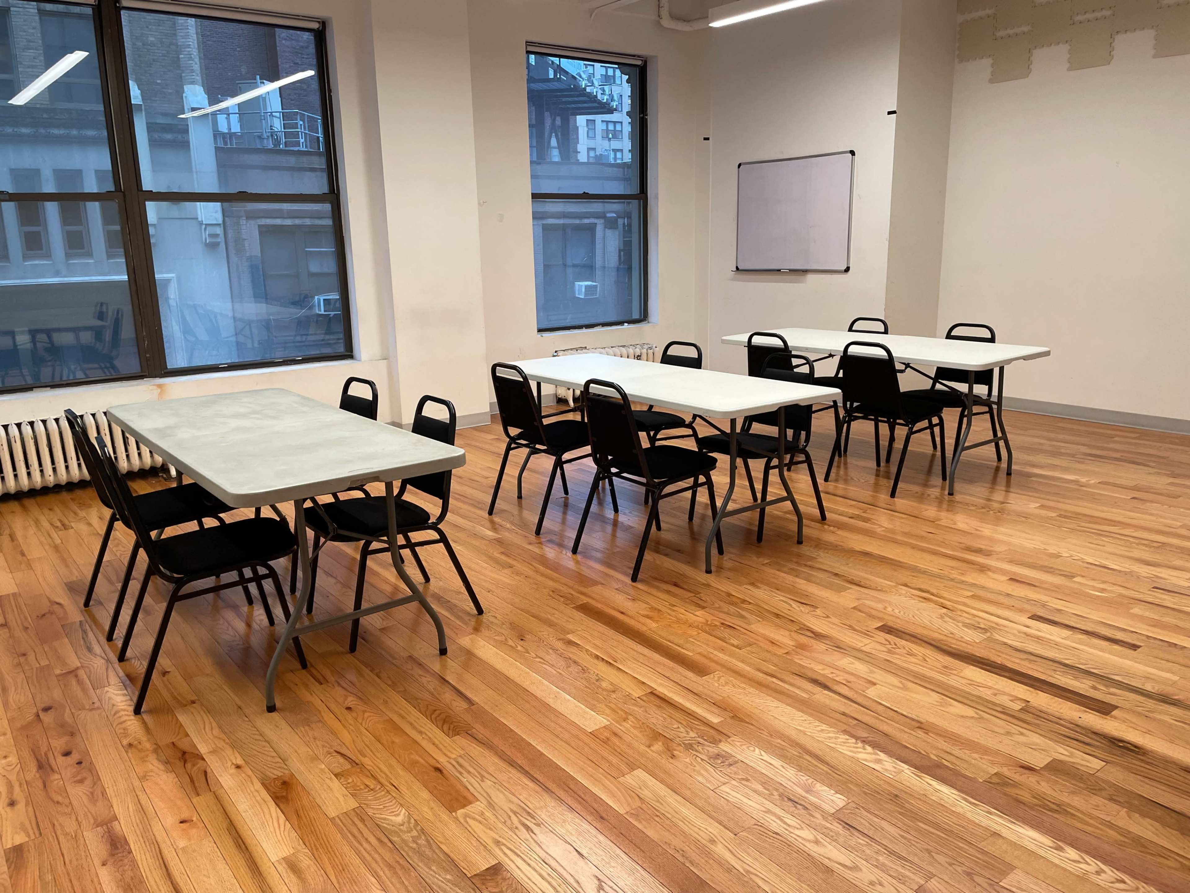 A spacious room with hardwood floors contains several tables and chairs arranged neatly.