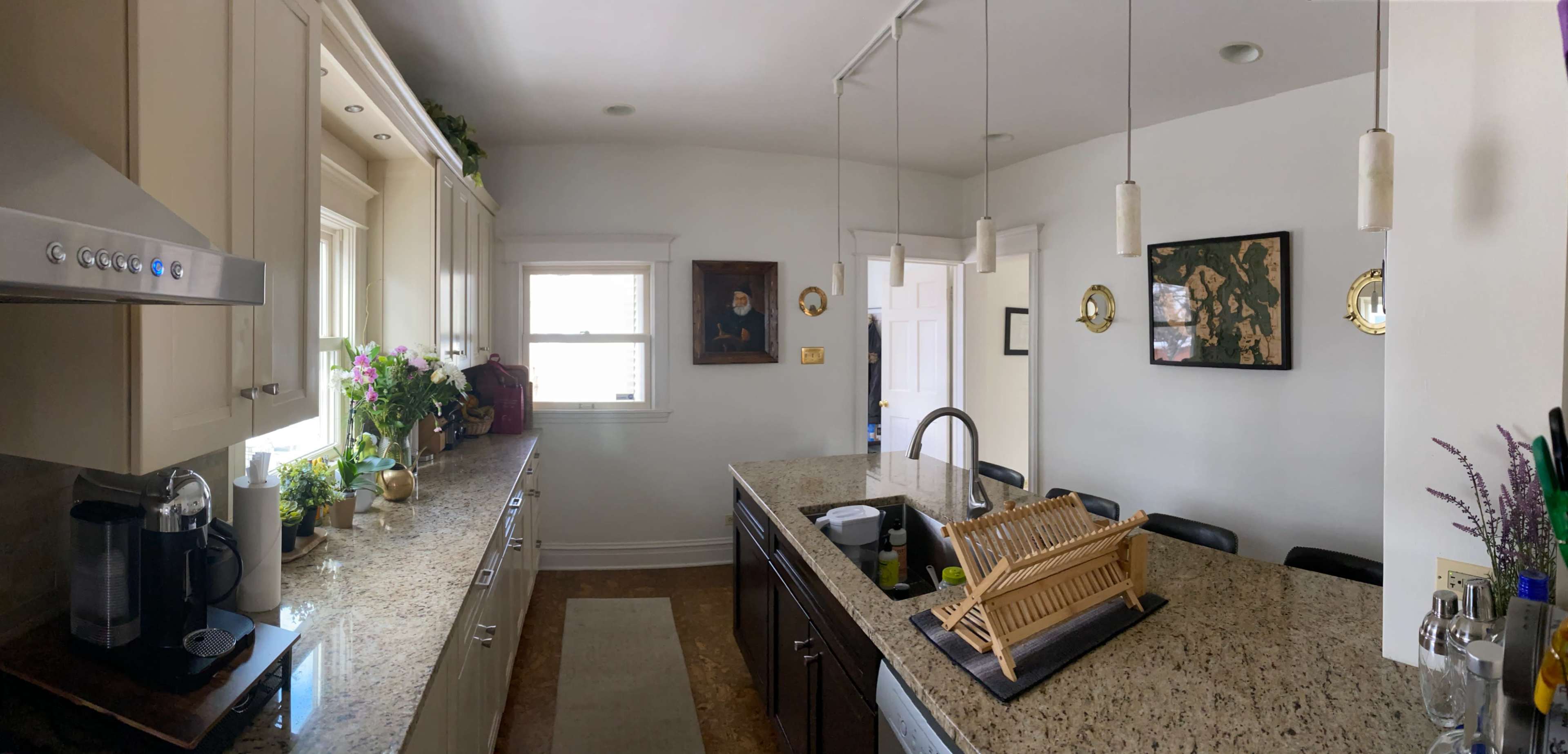 A modern kitchen features granite countertops, stainless steel appliances, and a wooden drying rack beside a sink.